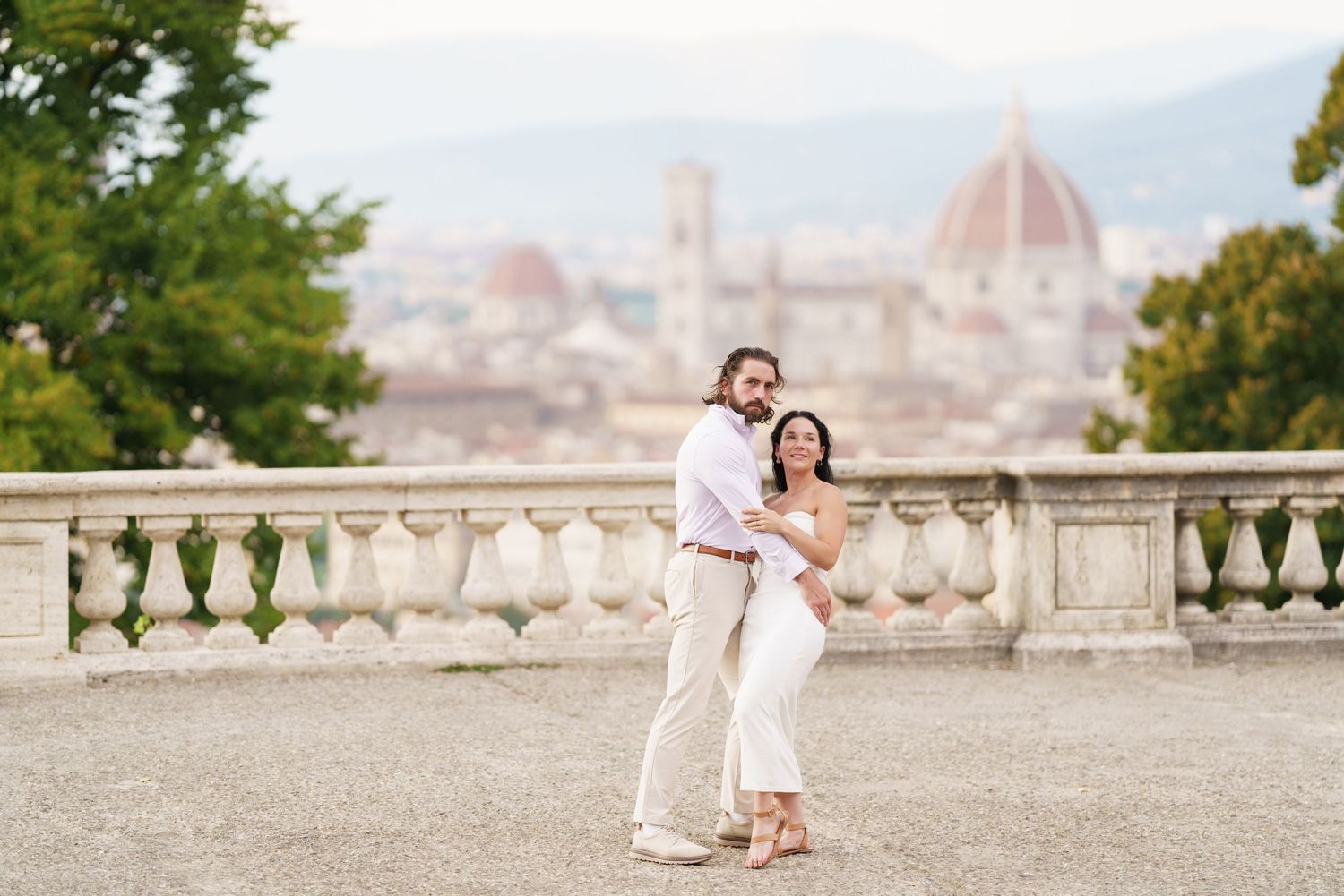 Couple embraces on a scenic overlook with Florence's iconic Duomo cathedral visible in the distance.