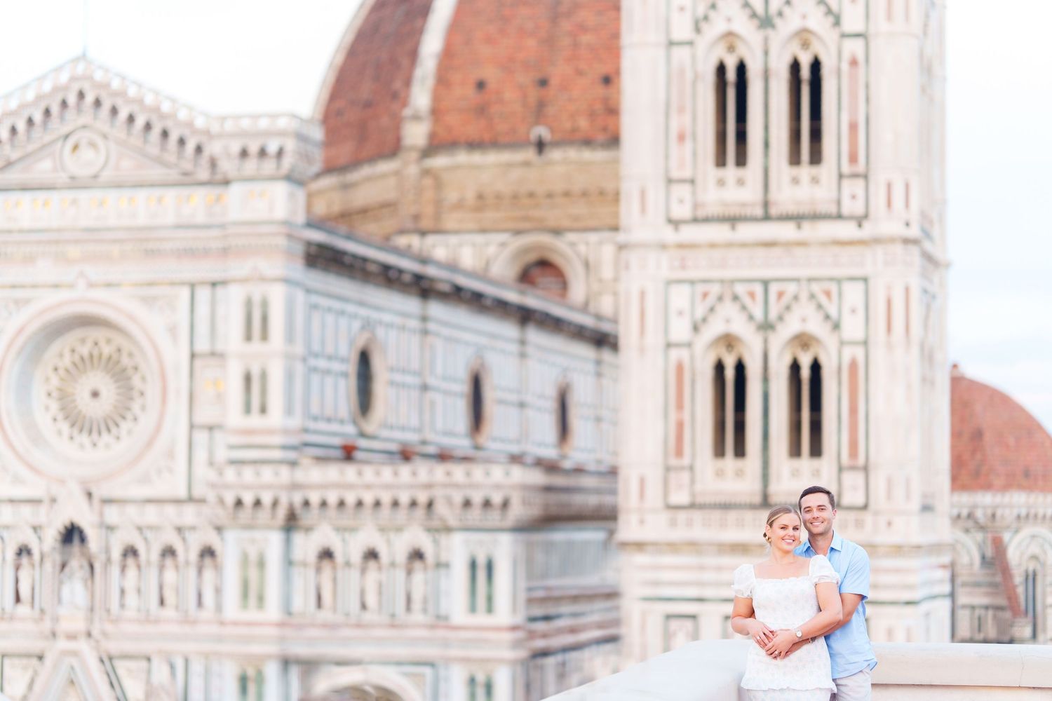 The ornate facade of Florence Cathedral with its iconic dome rises majestically against a bright blue sky in Italy.