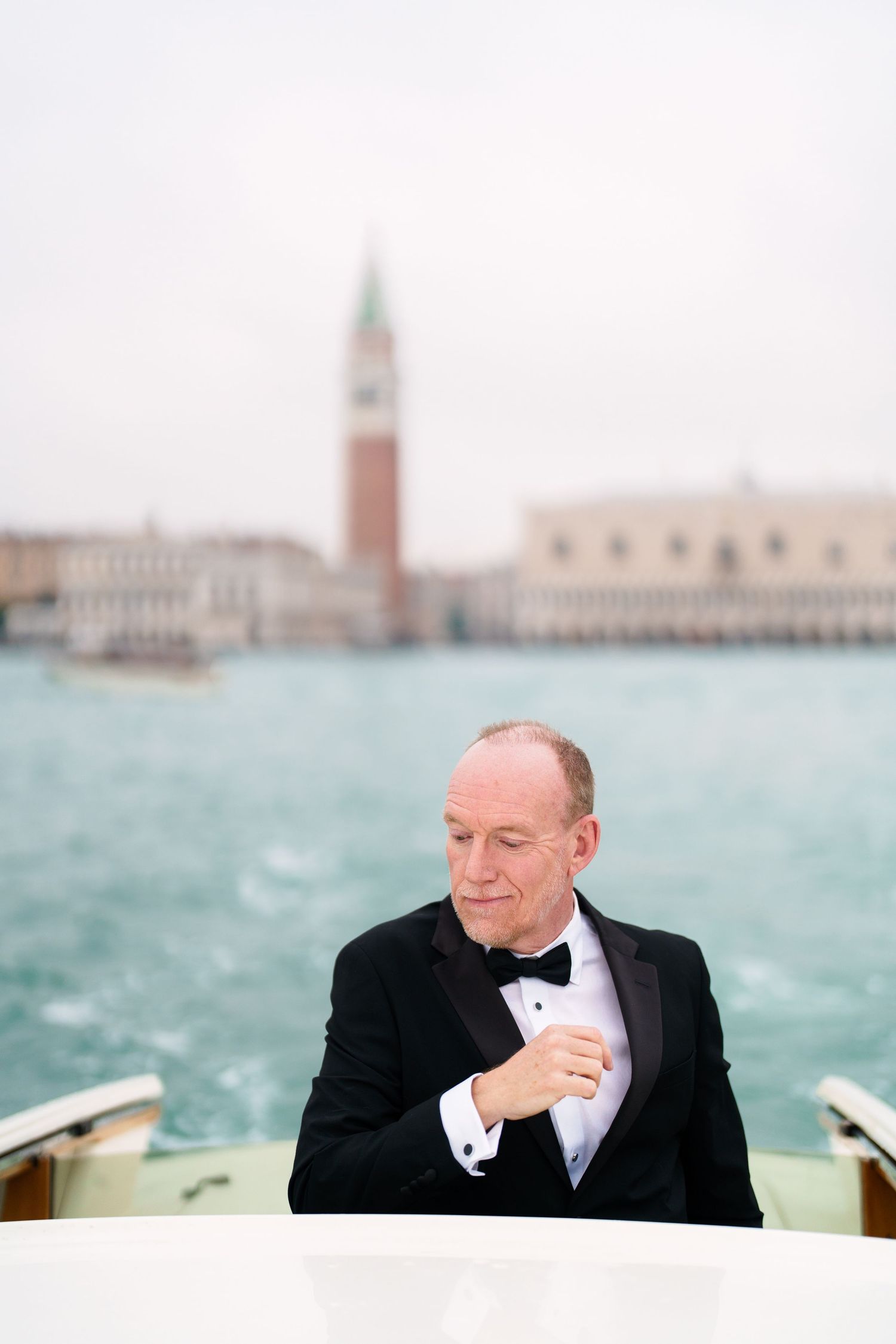 Panoramic view of Venice's St Mark's Square and iconic buildings seen across the lagoon on a cloudy day.