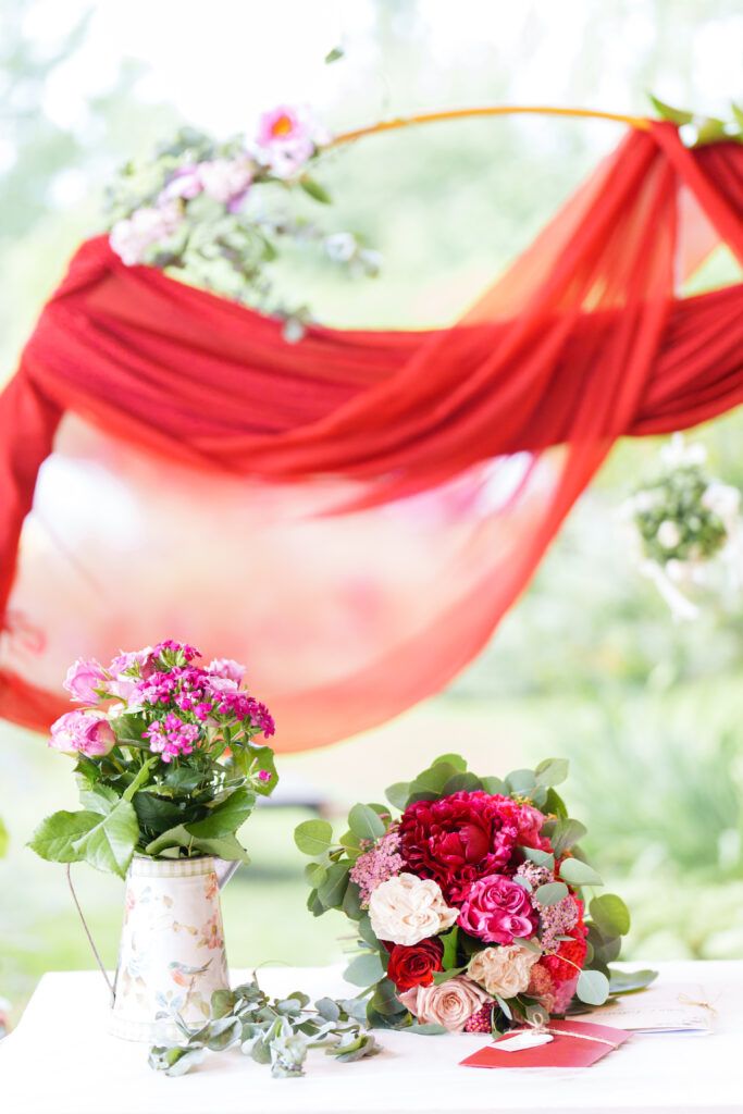 Red fabric draping and floral arrangements create elegant wedding decor.