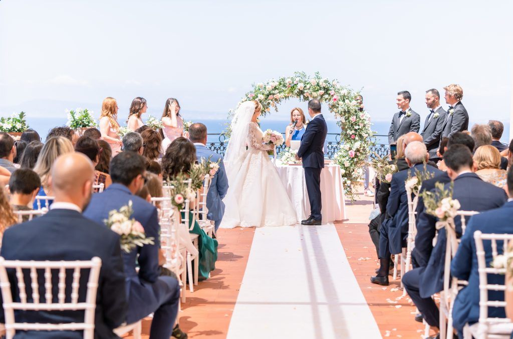 Elegant outdoor wedding ceremony setup with white chairs and floral arrangements.