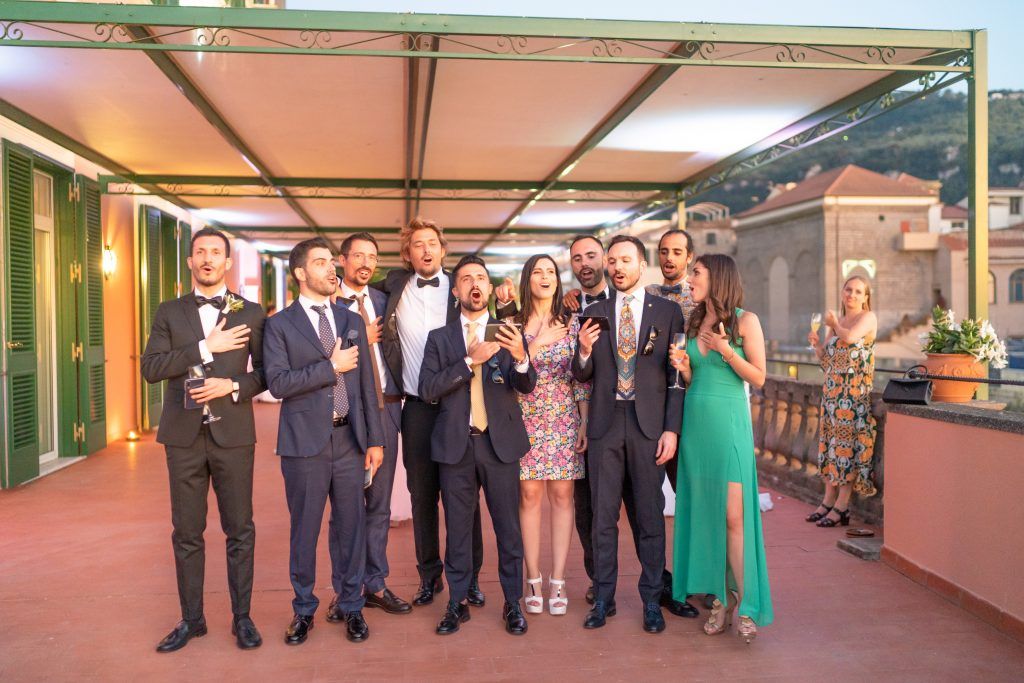 Wedding guests dancing together at an outdoor reception venue with warm lighting.