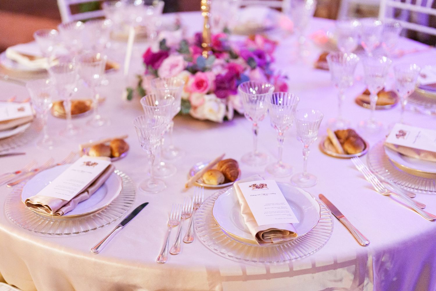 Detailed view of luxury table settings with crystal glasses and gold charger plates.