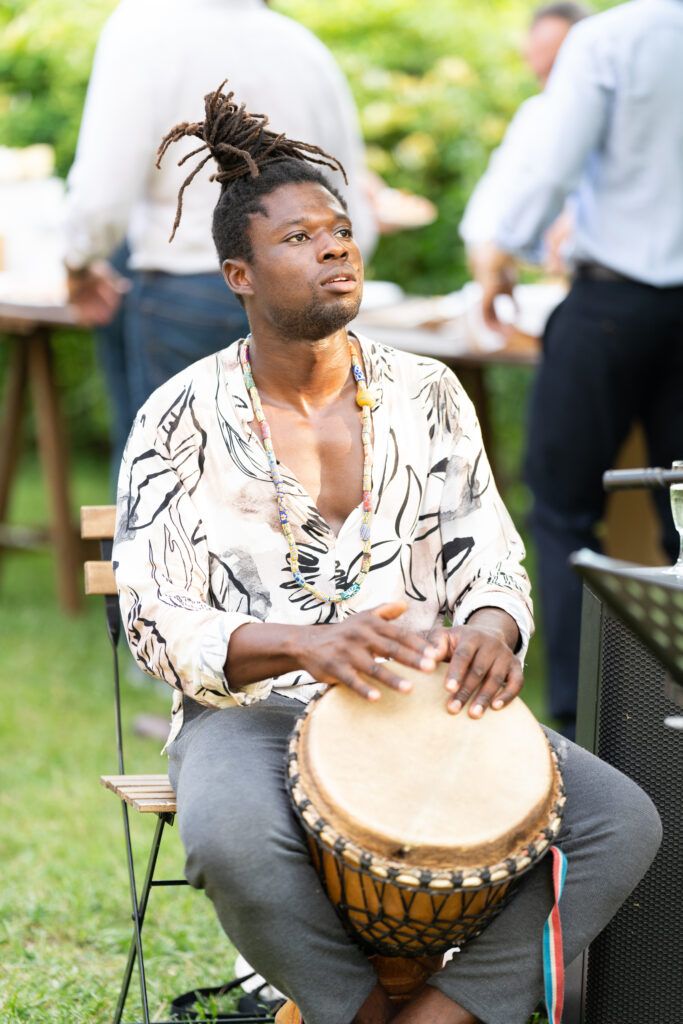Musician plays traditional djembe drum during outdoor celebration.