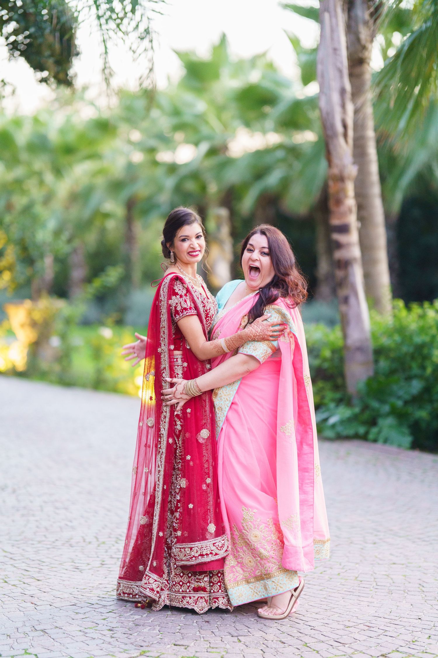 Joyful candid moment between friends wearing traditional Indian attire at an outdoor event.