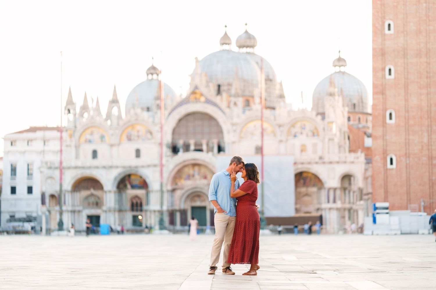 Couple sharing a romantic kiss in St. Mark's Square with the stunning Basilica di San Marco in Venice, Italy.
