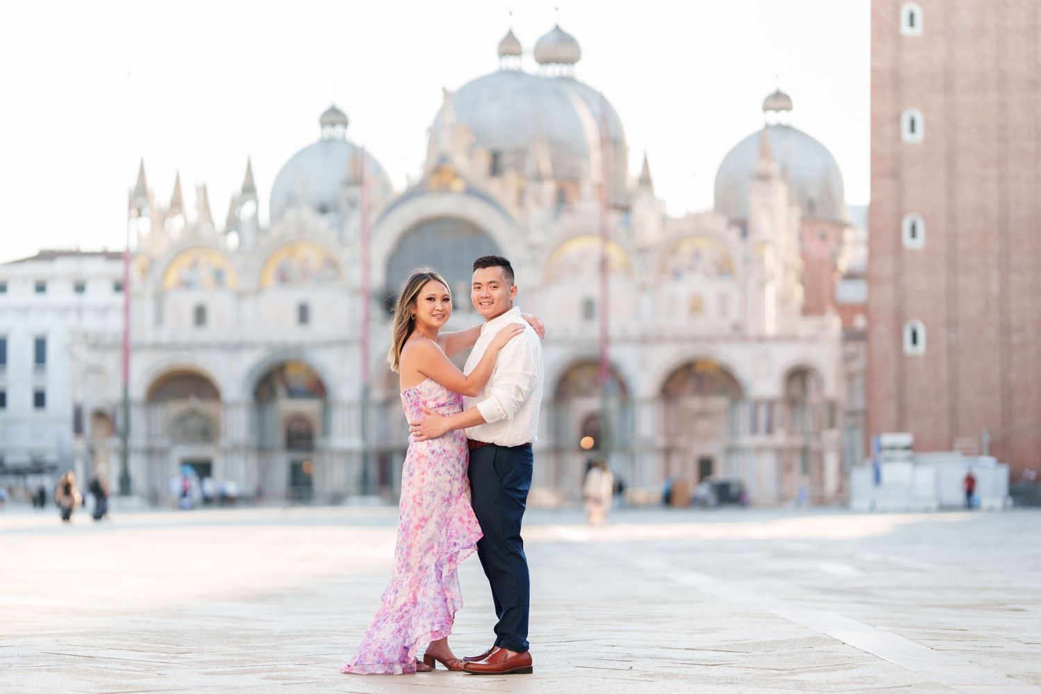 Couple posing romantically in St. Mark's Square, Venice, with the iconic Basilica di San Marco in the background.