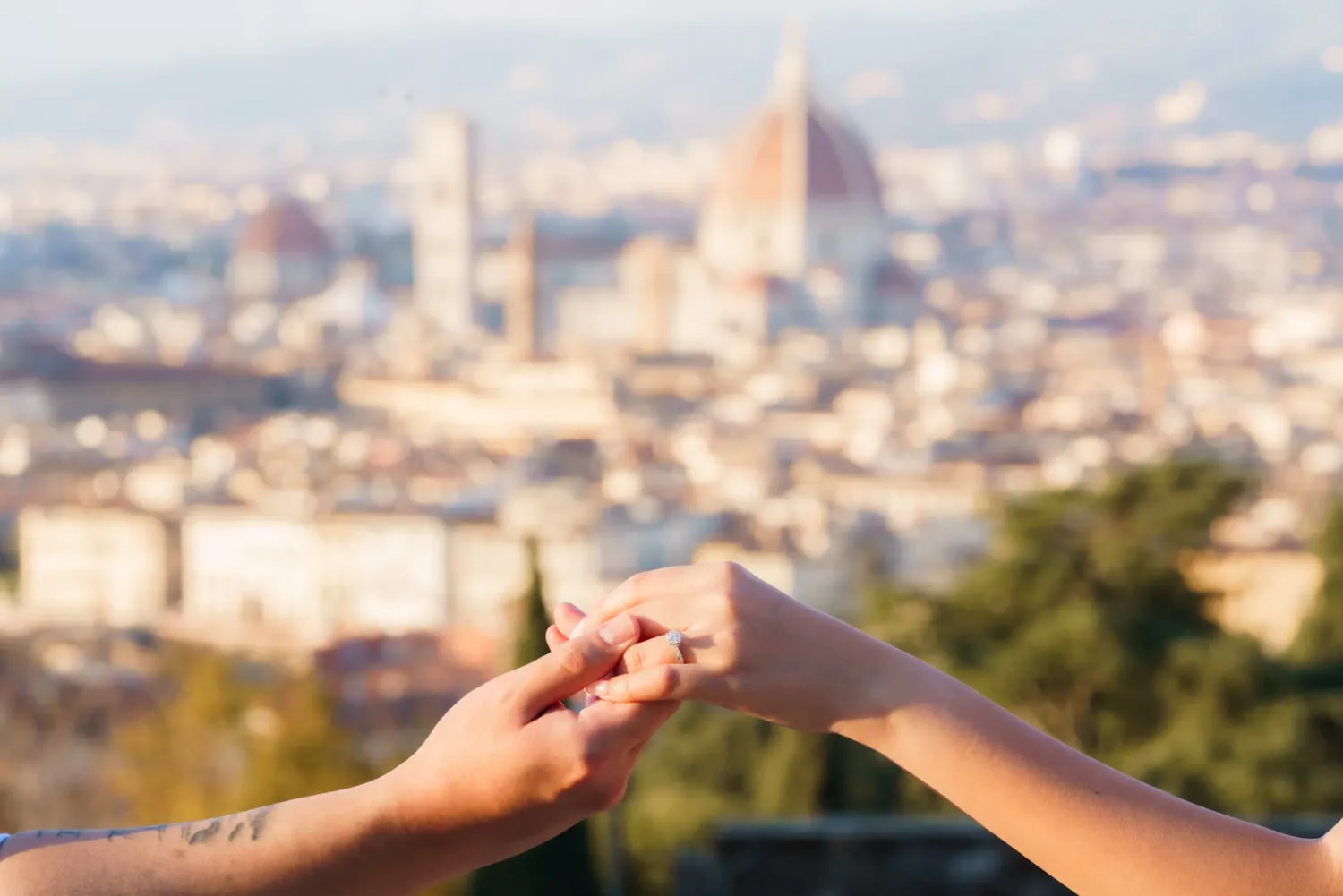 Two hands exchanging a piece of paper with Florence's iconic Duomo cathedral visible in the blurred cityscape background.