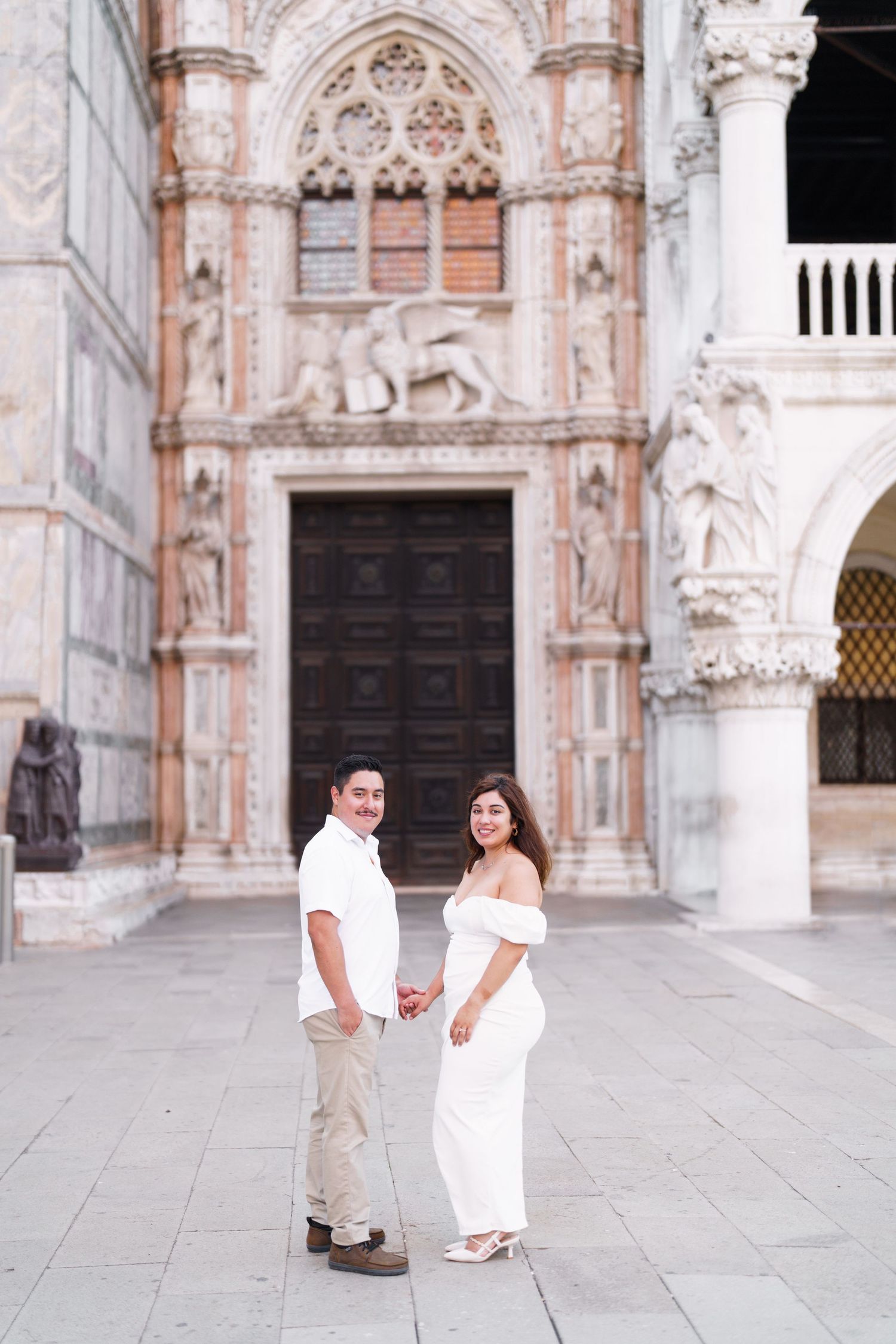 Romantic couple shares tender moments in front of an ornate Gothic cathedral entrance with intricate stone carvings.
