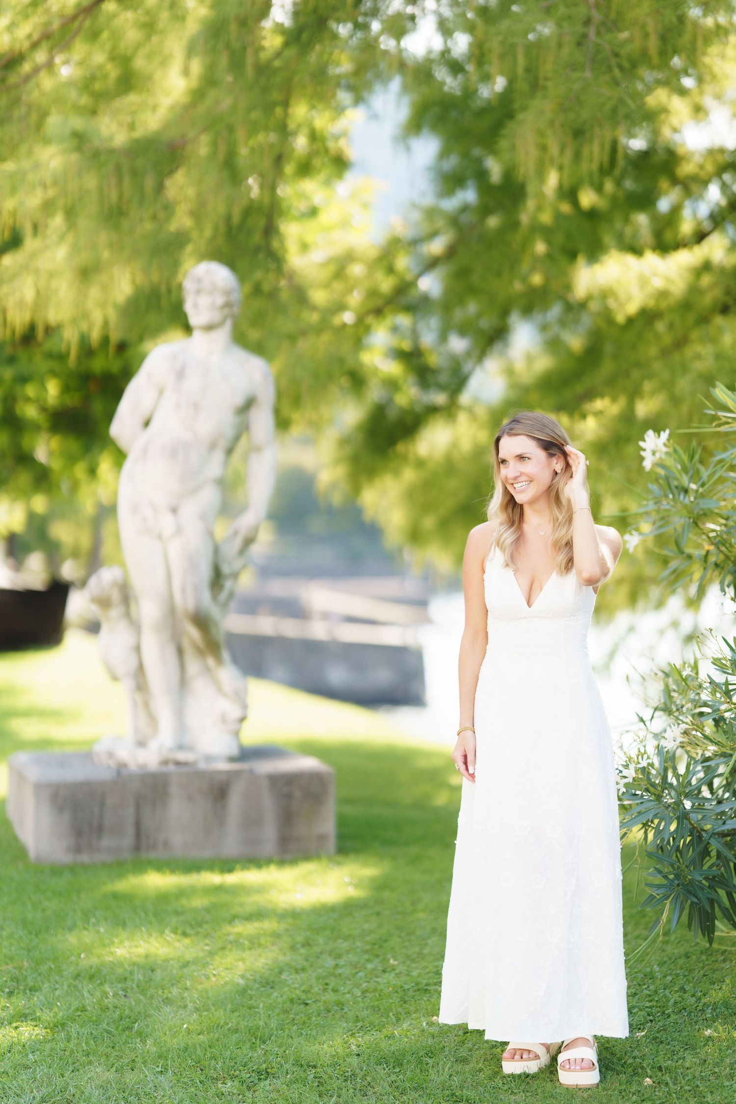 A series of photos showing a white summer dress against a lush green garden backdrop with stone sculptures.