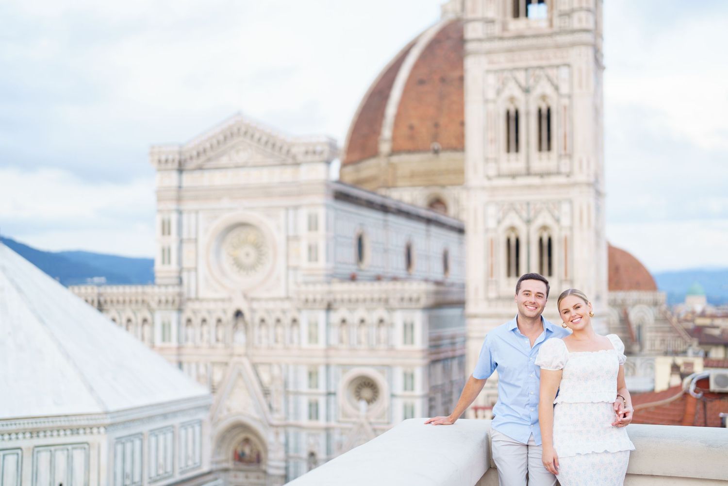 A couple stands in front of the Florence Cathedral and Duomo in Italy during a sunny day.
