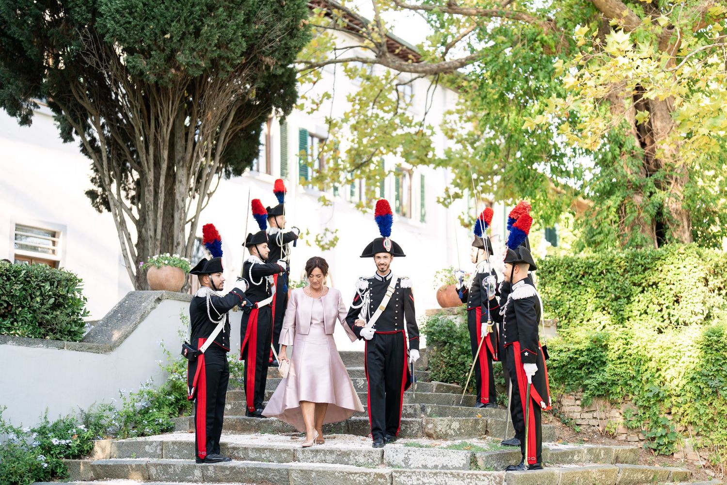 Military officers in formal dress uniforms stand at attention during an outdoor ceremony.