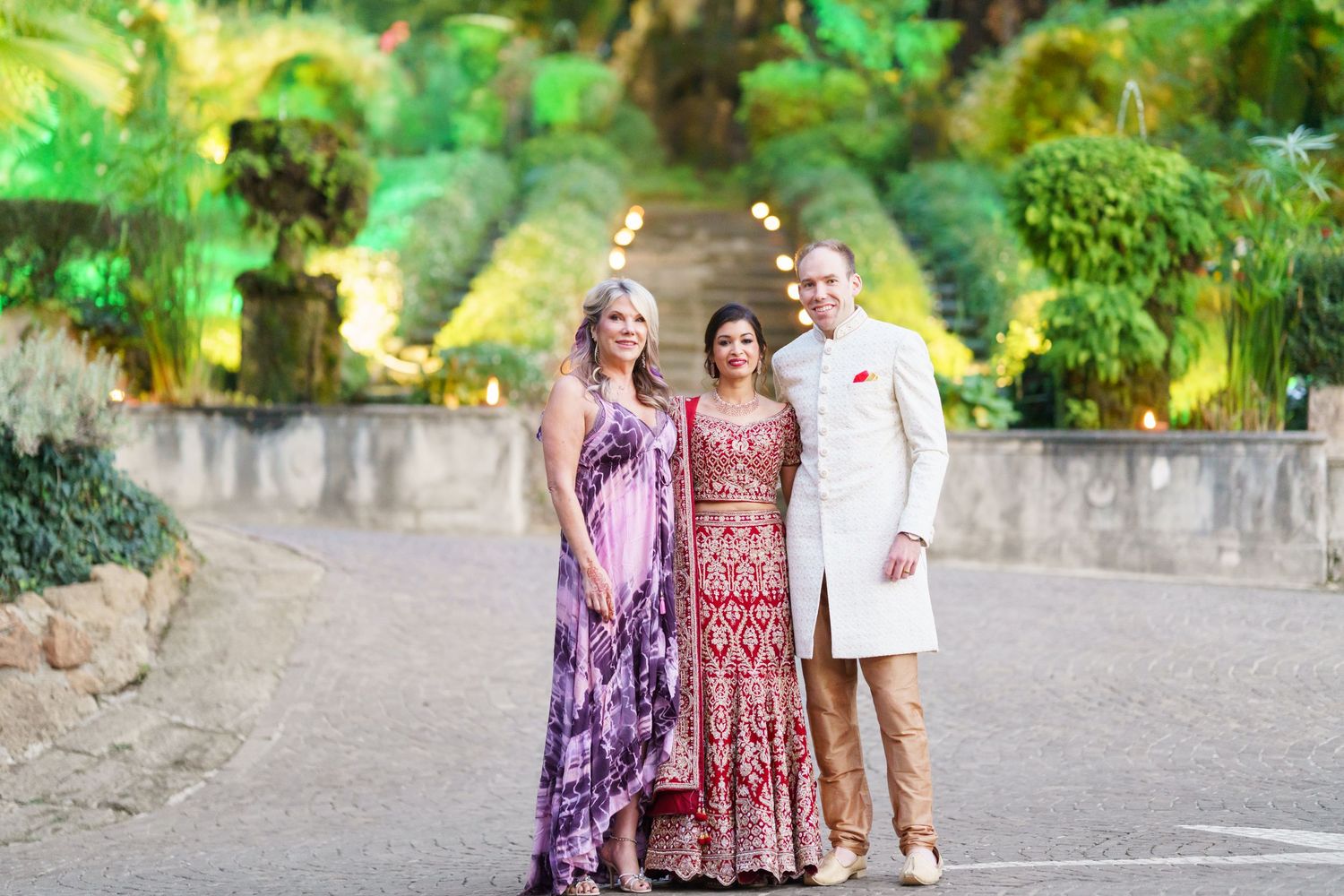 Group photo in a lush garden setting with people wearing colorful formal attire.