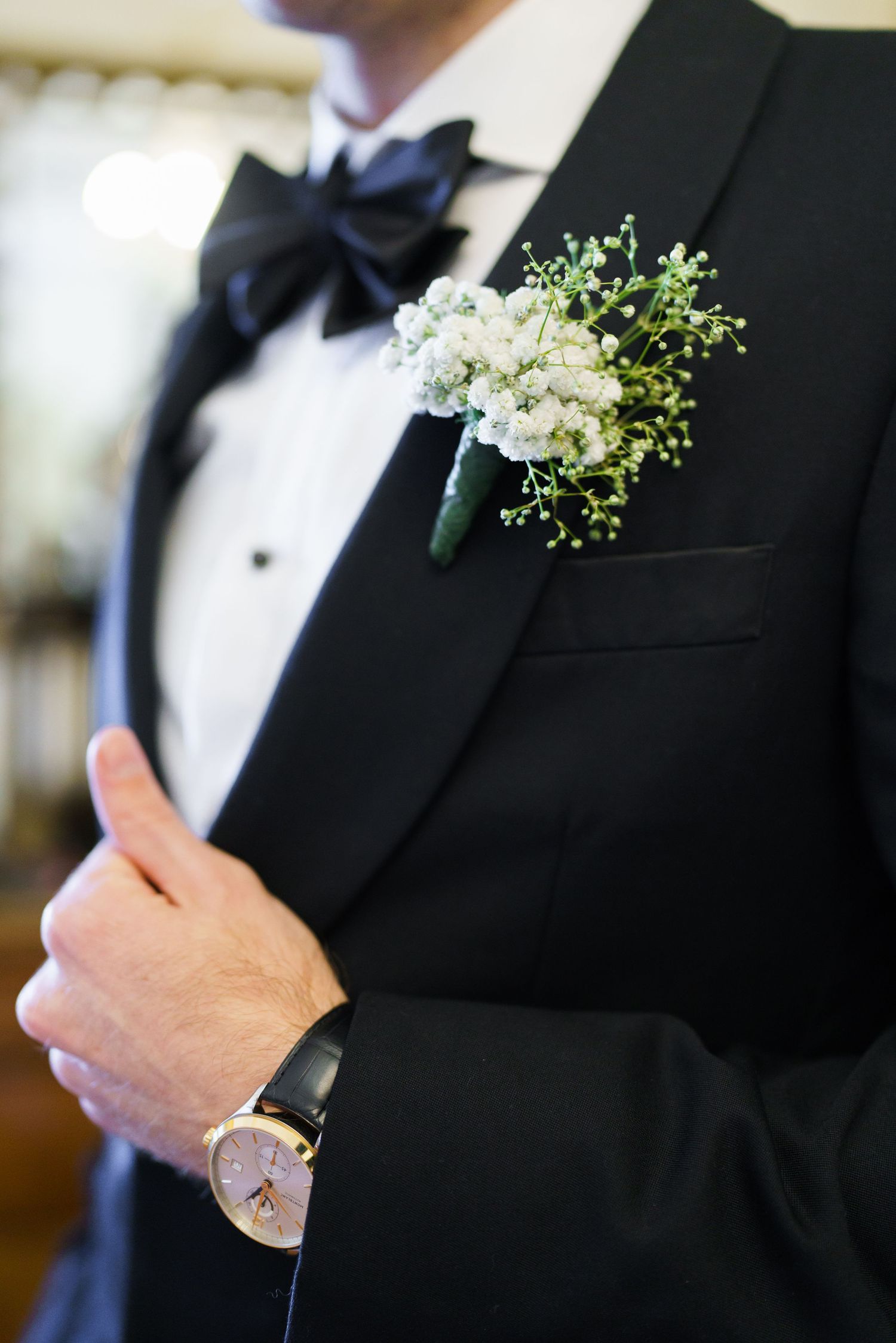 Close-up details of black tuxedo lapels with delicate white floral boutonnieres.