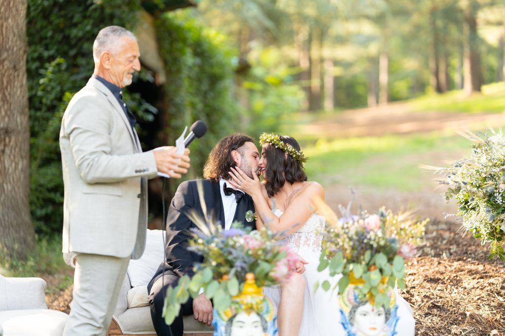 Wedding celebration with floral table decorations in a natural outdoor setting.