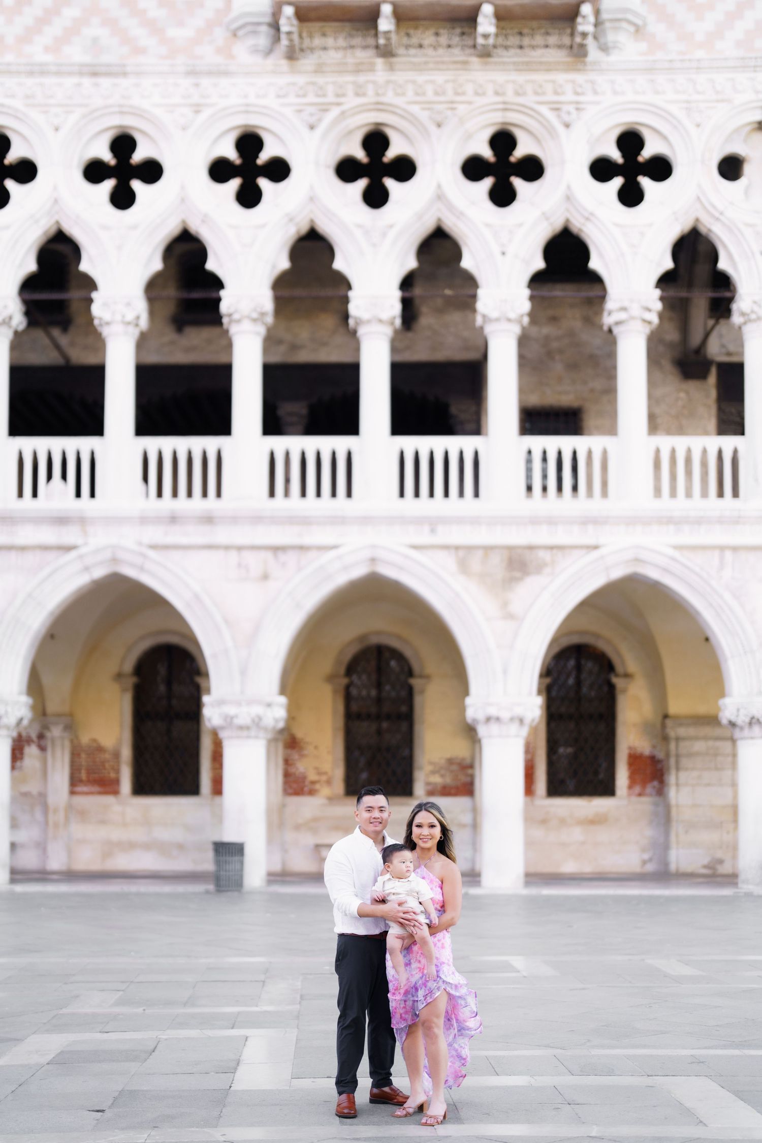Family posing in front of the Doge's Palace Gothic arches in Venice, Italy.