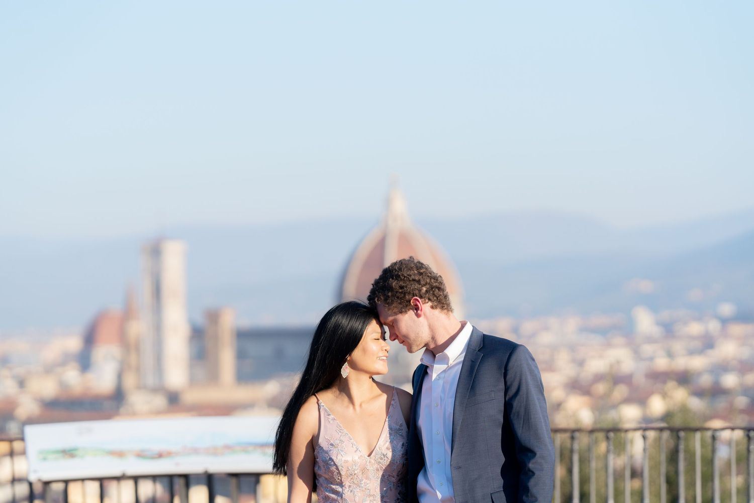 Couple embraces during romantic sunset photoshoot overlooking city skyline.