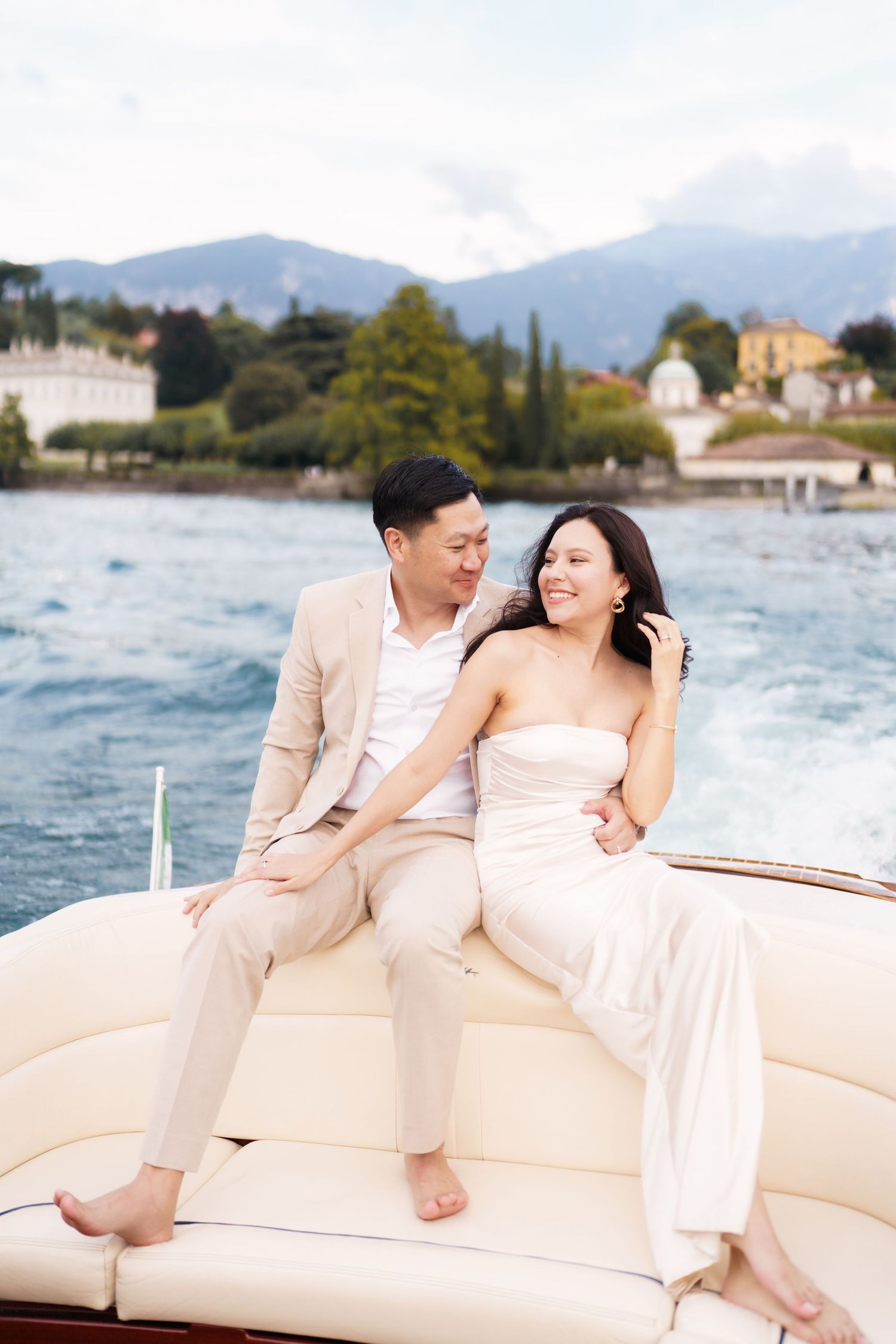 Couple enjoying a romantic moment together on a luxury boat with mountains and coastal scenery in the background.