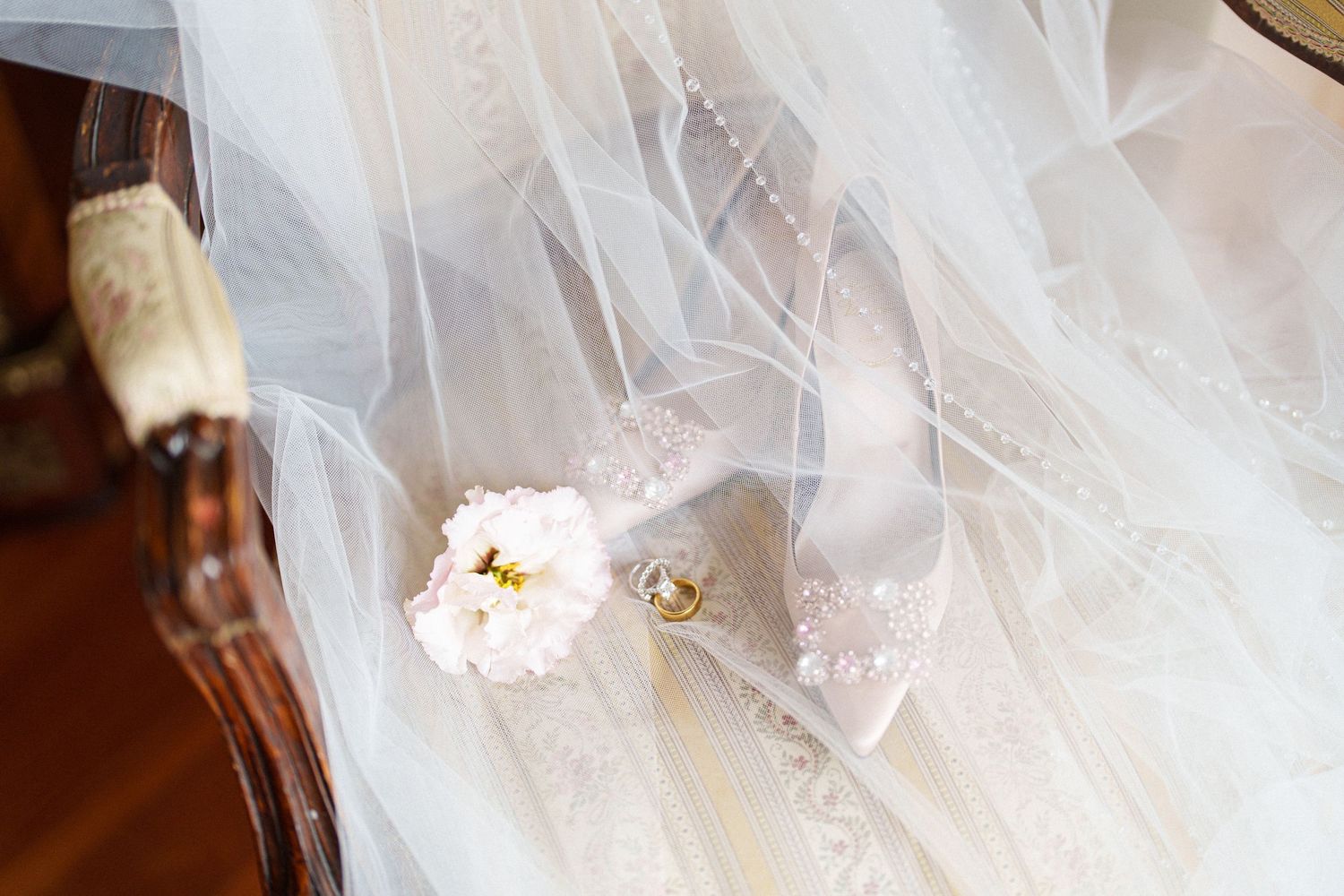 Soft white tulle fabric with scattered flowers and wedding accessories.