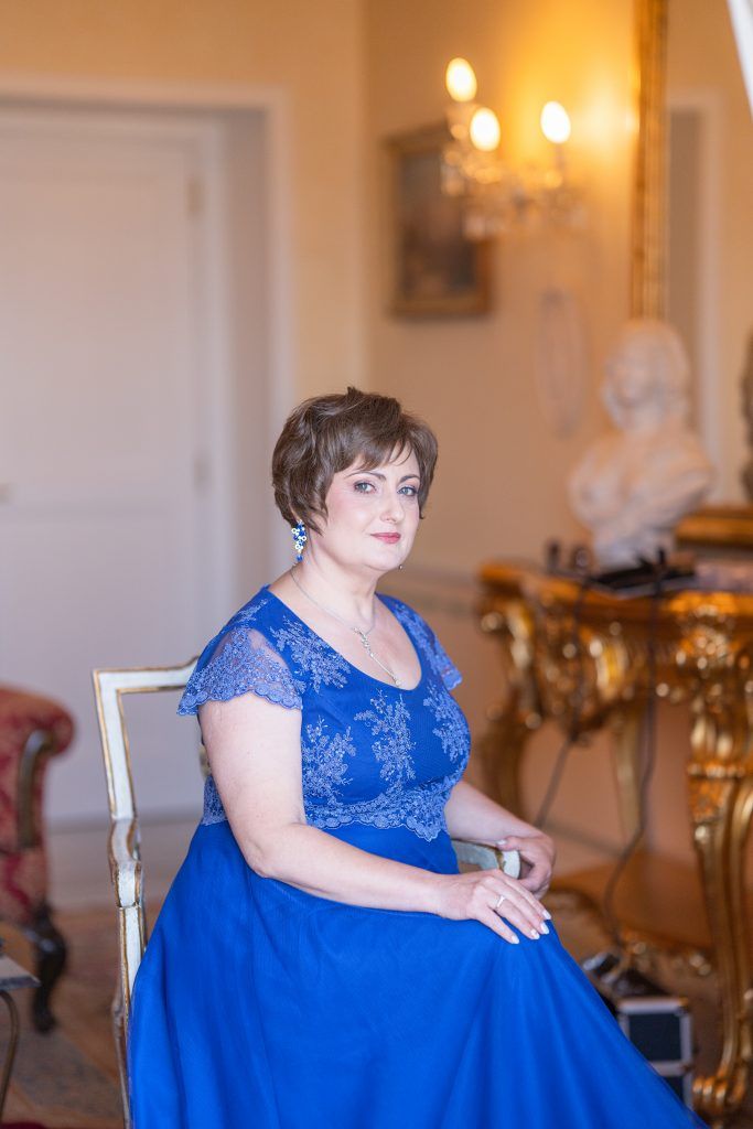 A wedding scene in an elegant room with warm lighting and a person wearing a royal blue dress.