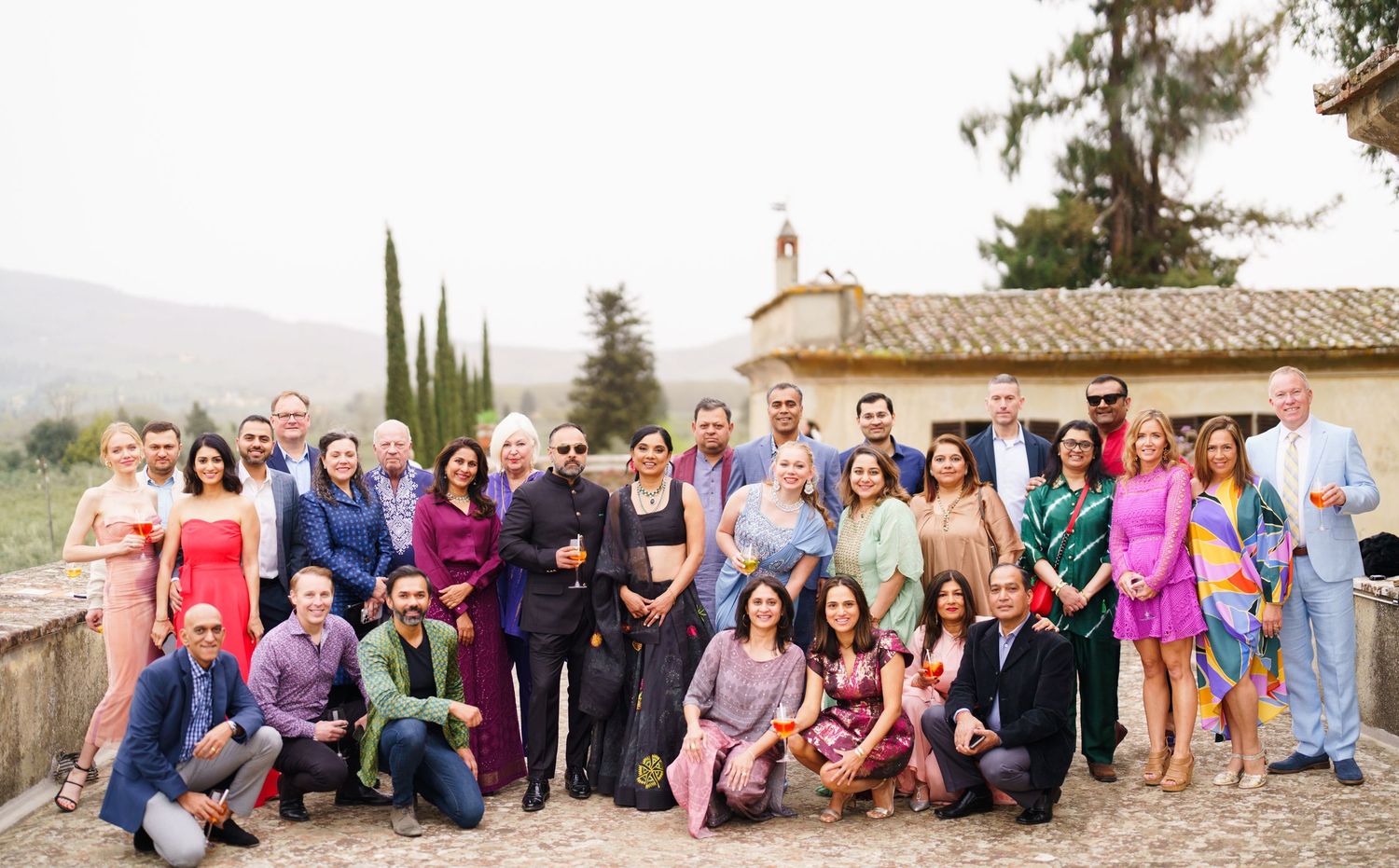 Group photo of wedding guests gathered outdoors at a rustic Mediterranean villa venue.