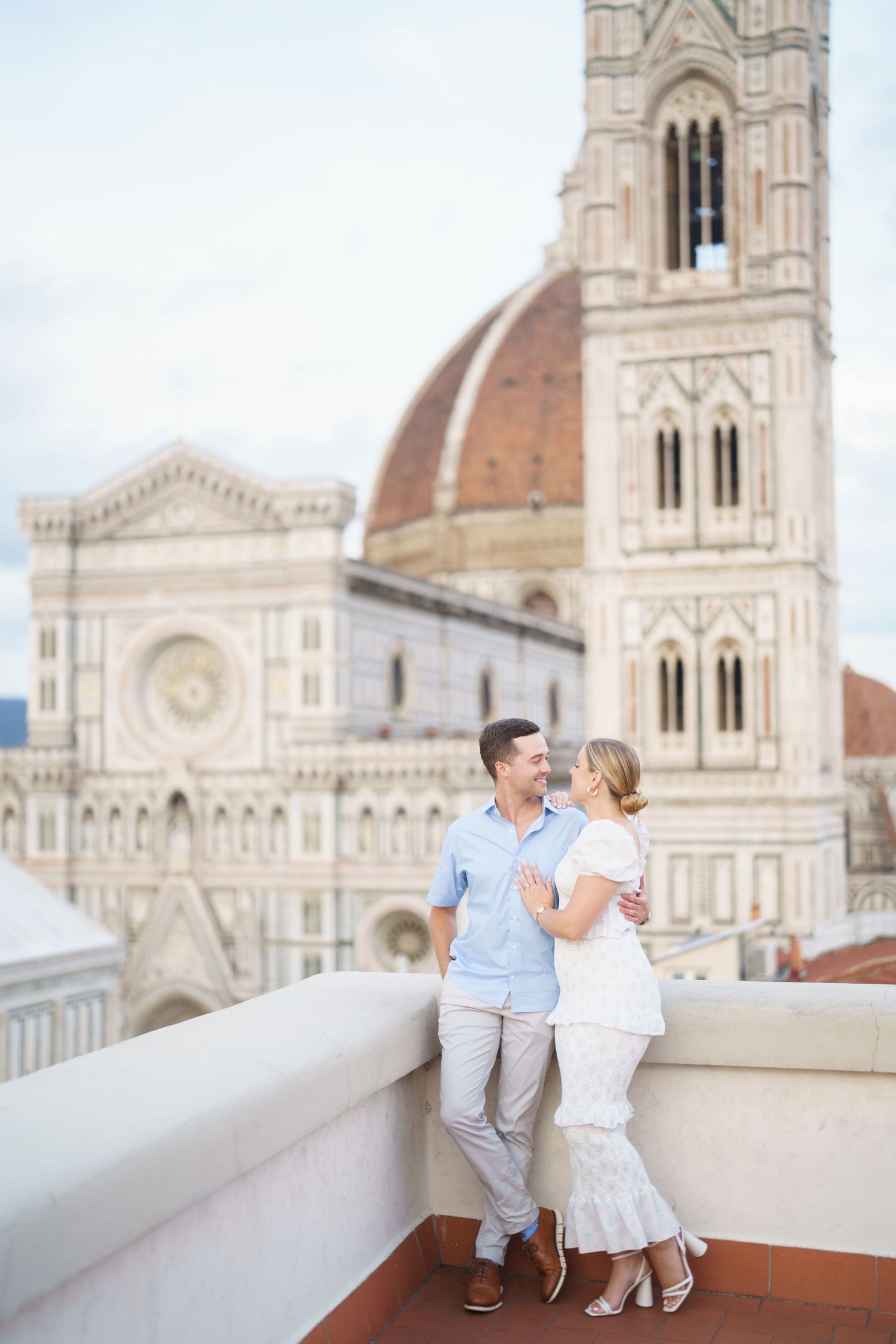 A couple shares a romantic moment on a rooftop terrace overlooking the Florence Cathedral and Duomo in Italy.