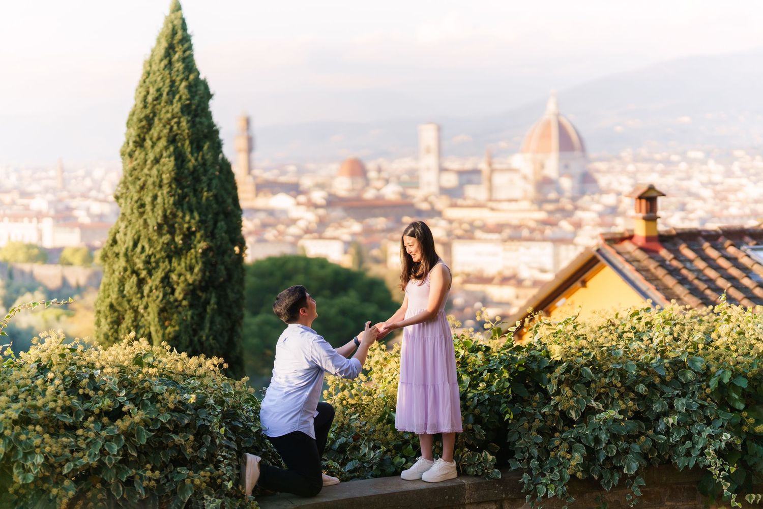 A romantic proposal moment overlooking the historic Florence skyline with the Duomo cathedral visible in the distance.