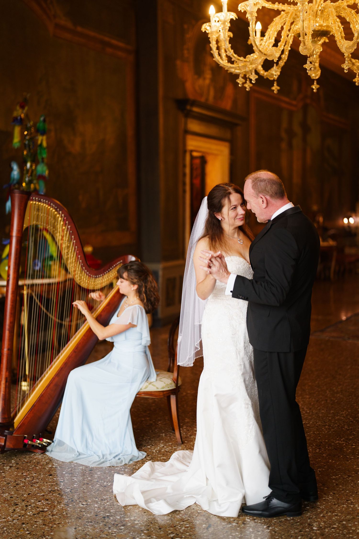 Romantic wedding photo series with couple and harp in an elegant candlelit ballroom setting.