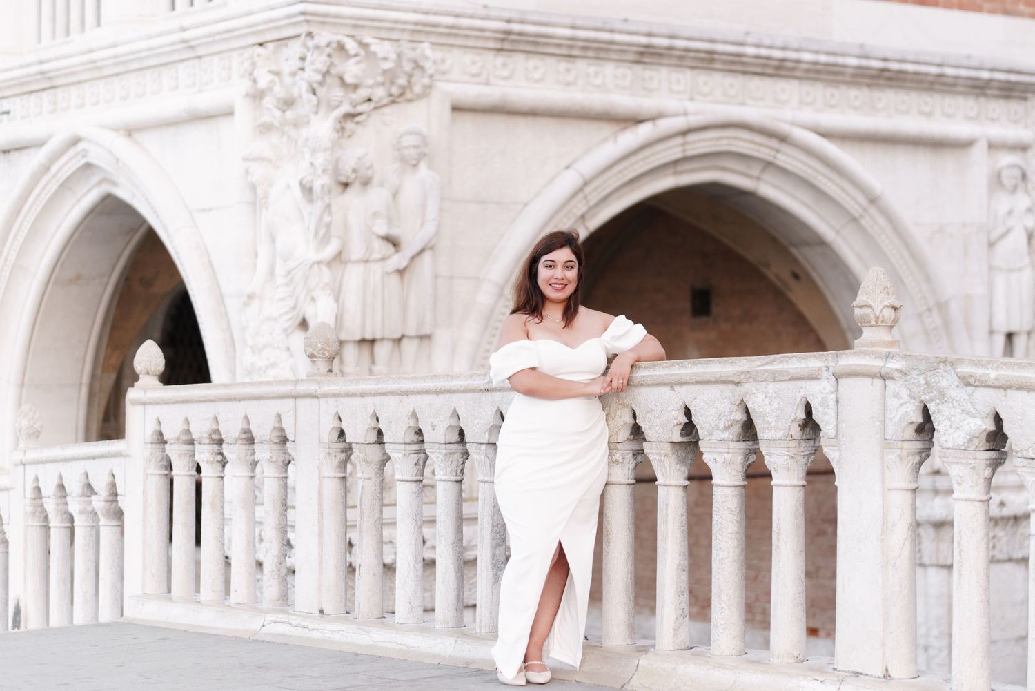 A couple shares a romantic moment against the elegant backdrop of Venice's Doge's Palace and its ornate stone arches.