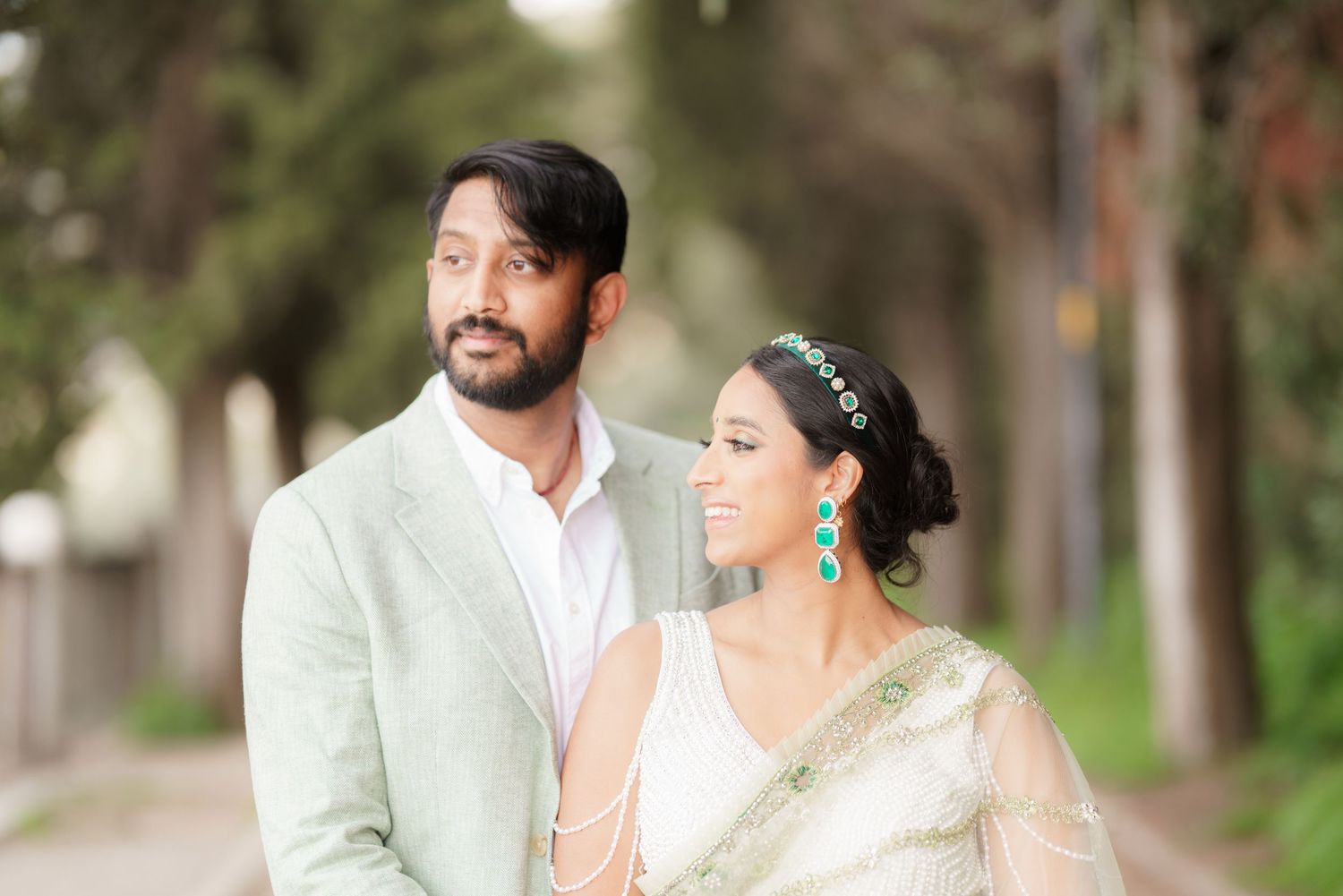 A bride and groom share romantic moments in an outdoor garden setting during their wedding photoshoot.
