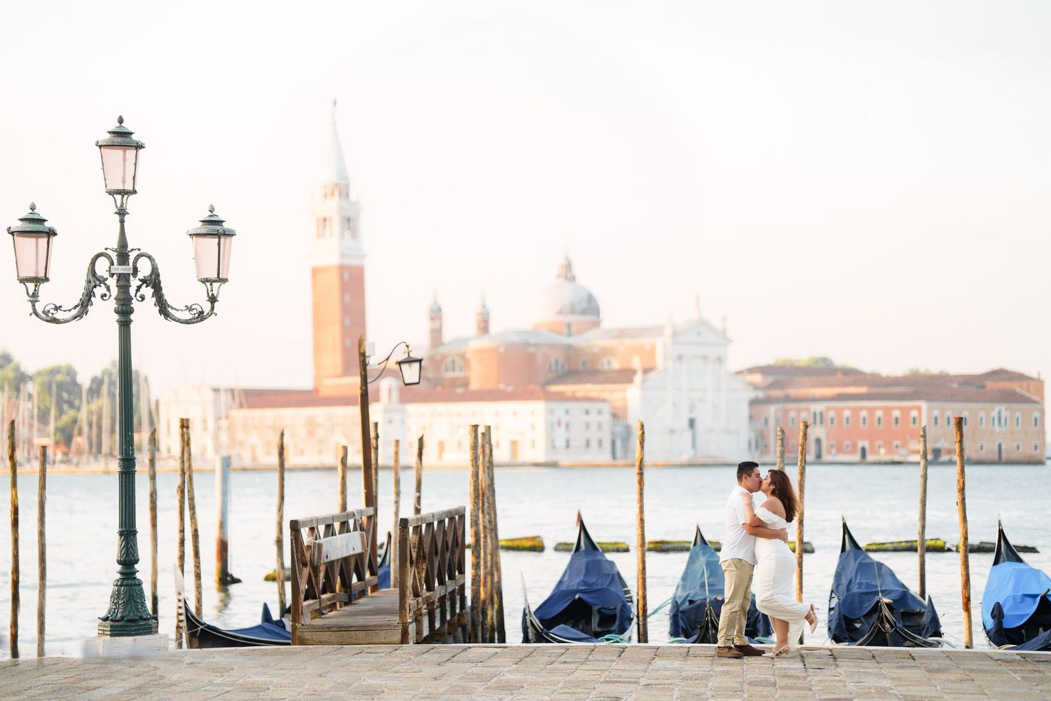 photographer venice Ornate street lamps and gondolas line the misty waterfront of Venice with San Giorgio Maggiore church in the background.