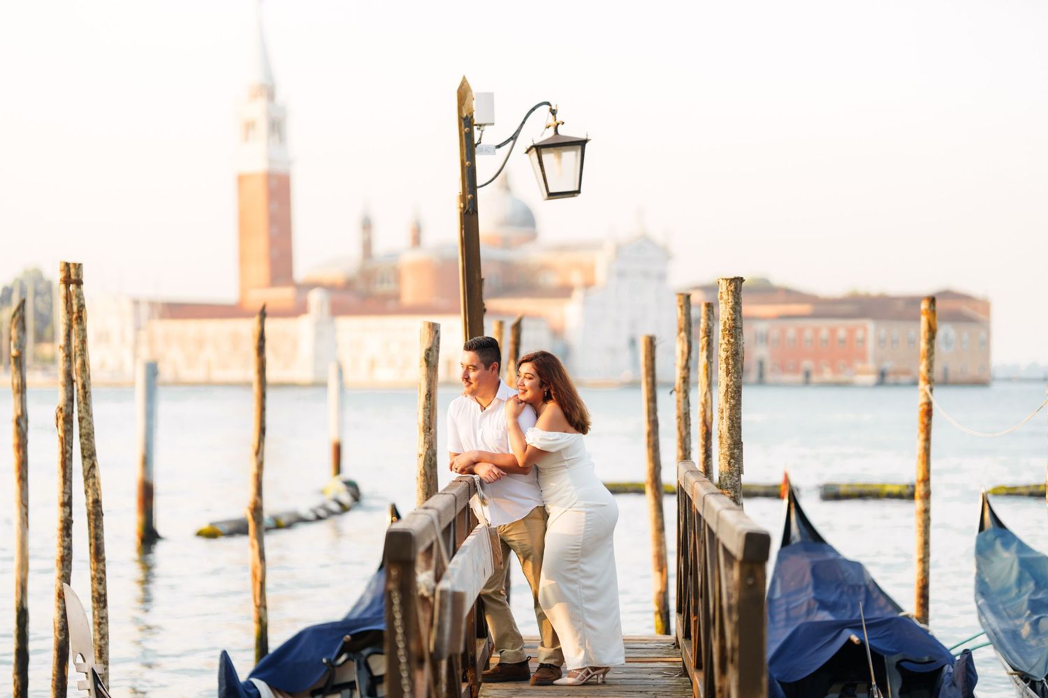 photographer venice Gondolas float along the misty canals of Venice with historic buildings and wooden posts rising from the water.