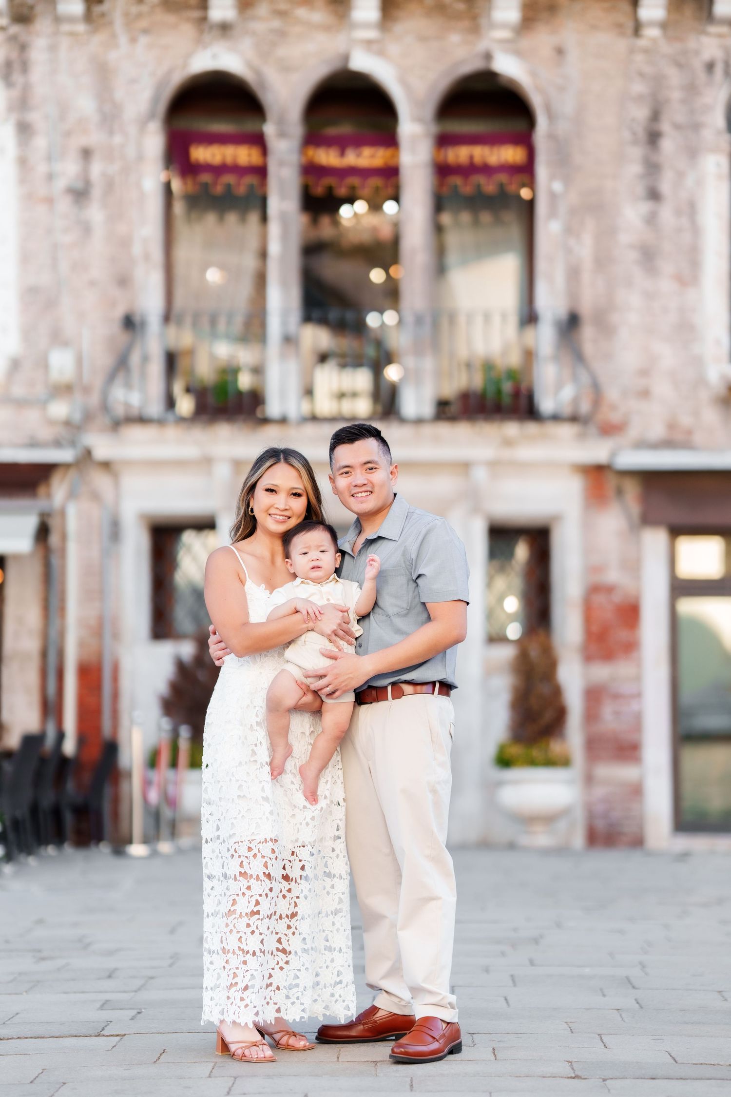 Young Asian family with baby posing in front of Hotel Palazzo Vitturi in Venice, Italy.