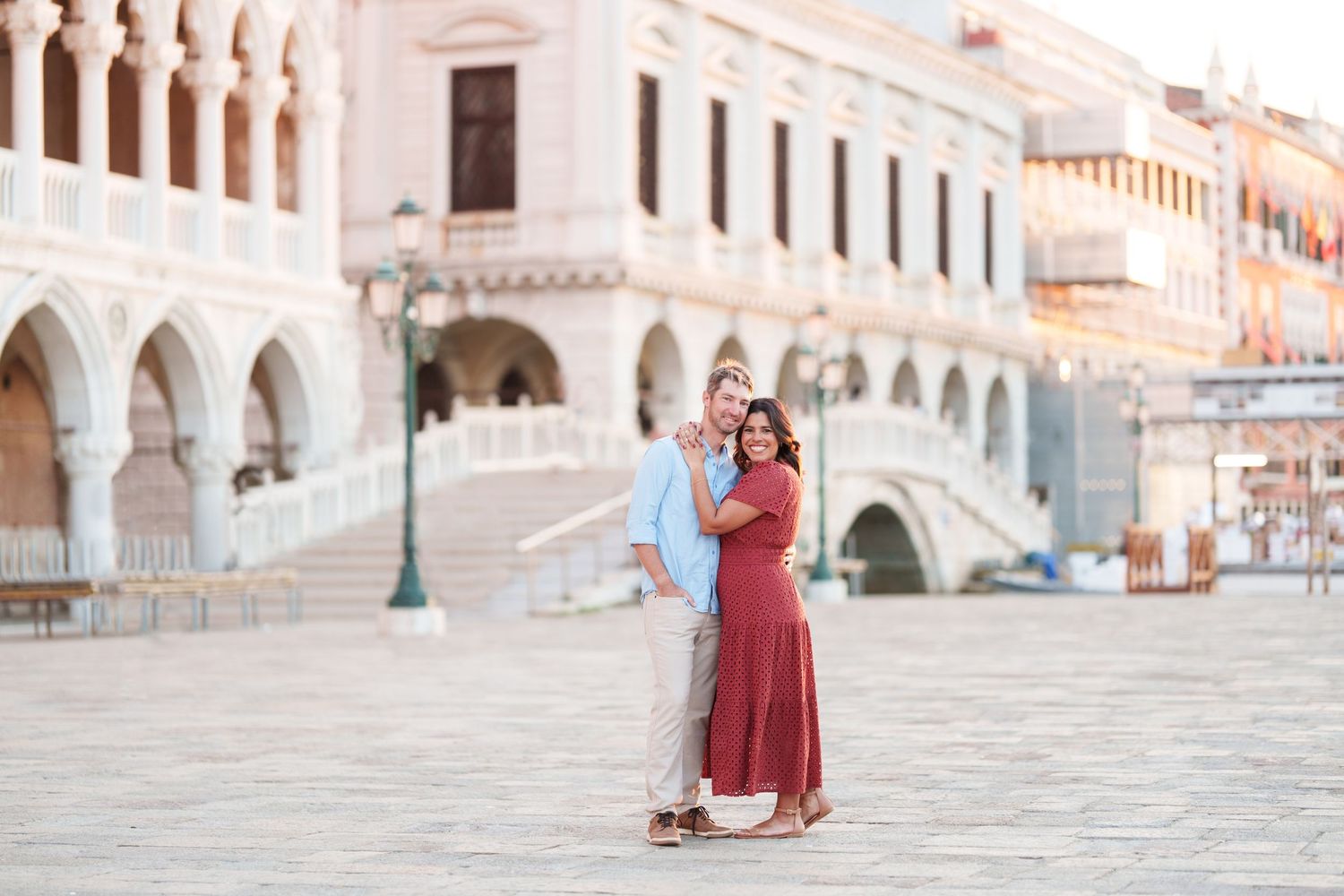 Couple embracing at St. Mark's Square in Venice, Italy, with the Doge's Palace in the background.