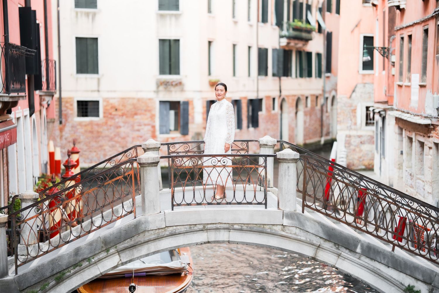 Woman in white dress standing on a charming bridge over a Venetian canal in Venice, Italy.