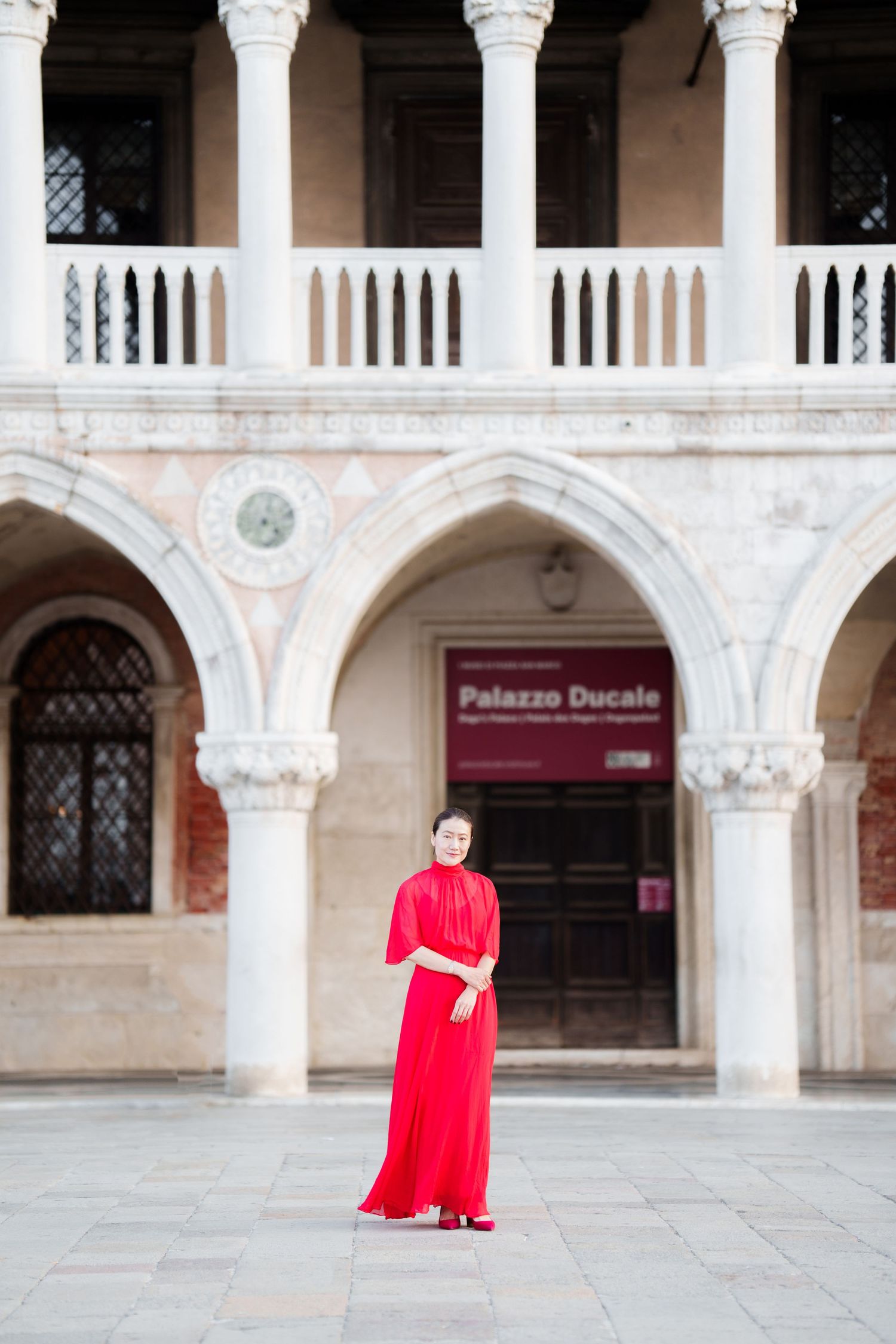 Woman in red dress standing in courtyard of Palazzo Ducale, Venice, Italy.