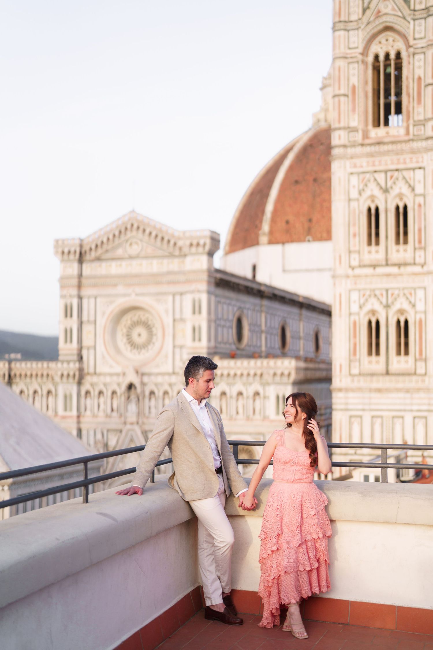 A couple stands on a terrace overlooking the Florence Cathedral and Brunelleschi's Dome in Italy.