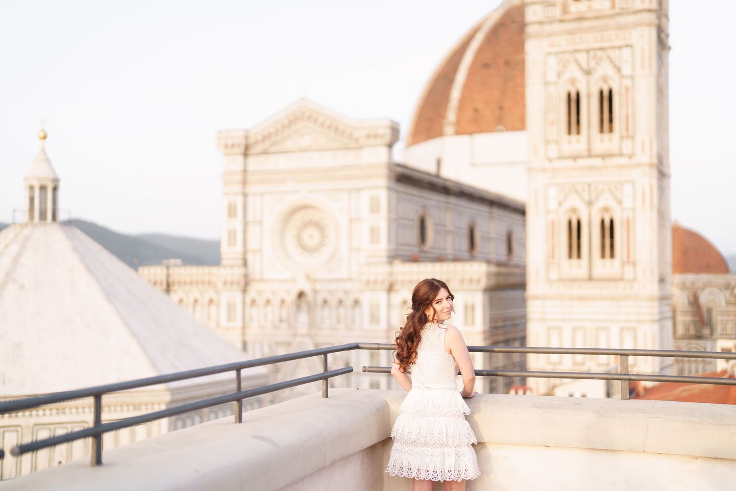 Woman in pink dress poses in front of Florence Cathedral during sunrise in Italy.