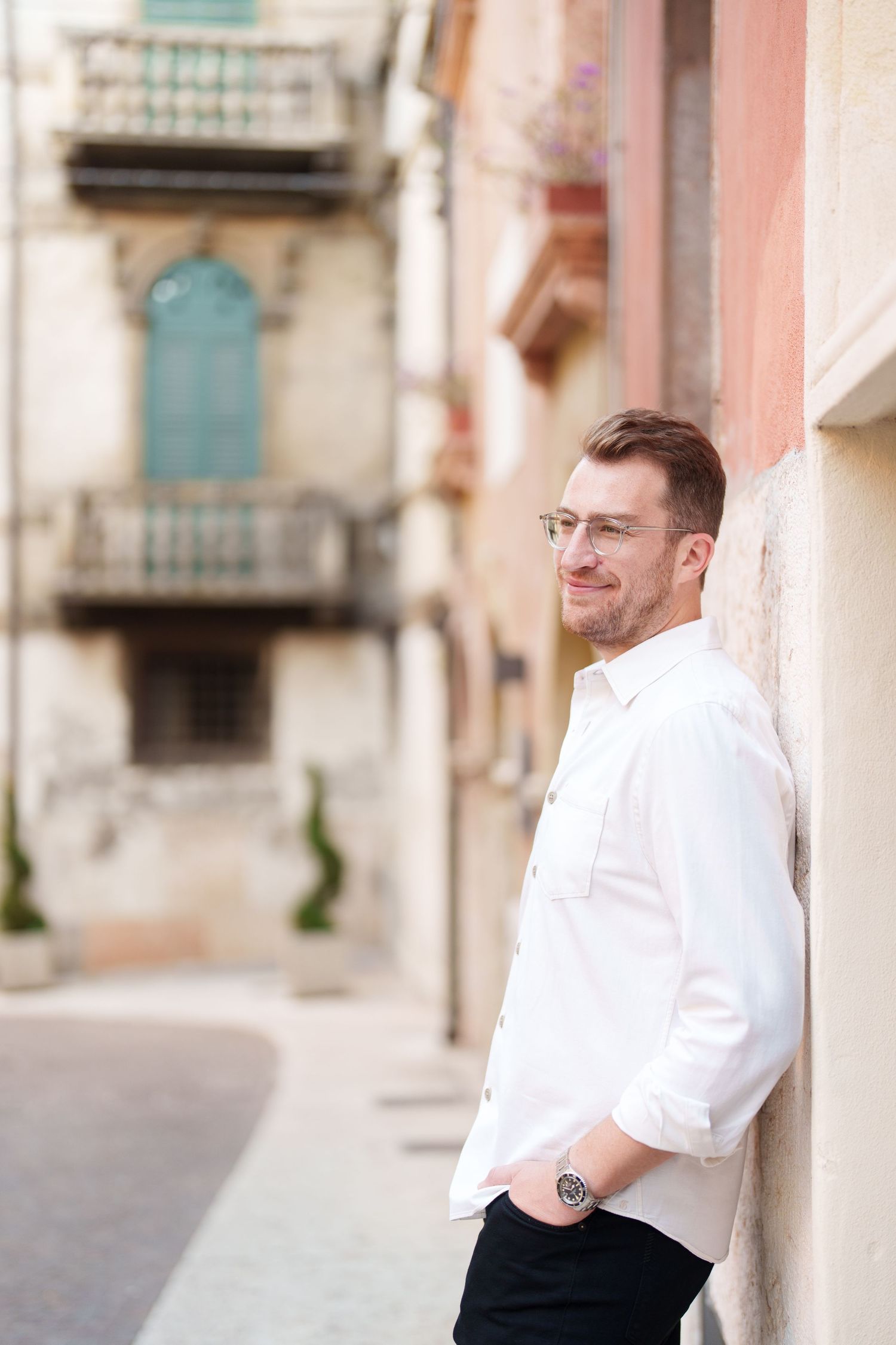 A series of five photos showing a person in a white dress shirt and black pants posing against a building wall.