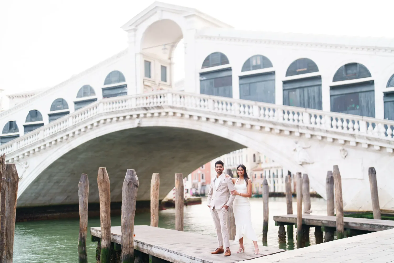A scenic view of the Rialto Bridge over the Grand Canal in Venice with gondolas passing underneath.