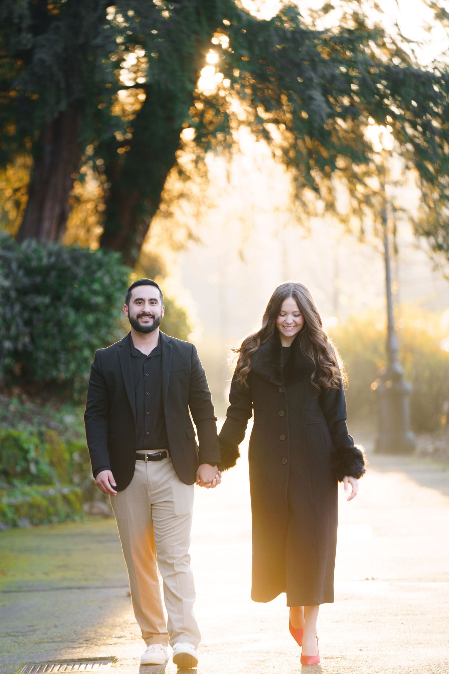 A couple walks together through a sunlit park during golden hour, creating a warm and romantic atmosphere.