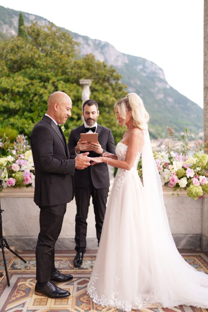 Wedding ceremony moments captured under ornate columns with mountain backdrop and pink floral arrangements.