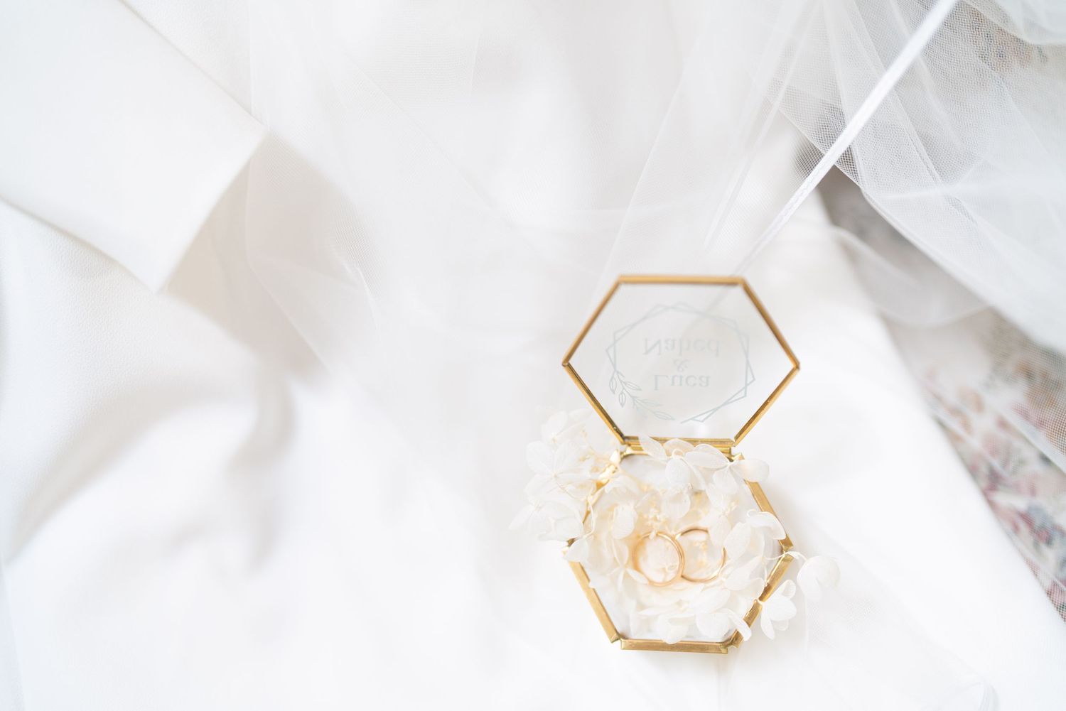 Delicate gold hexagonal jewelry detail on white fabric background.