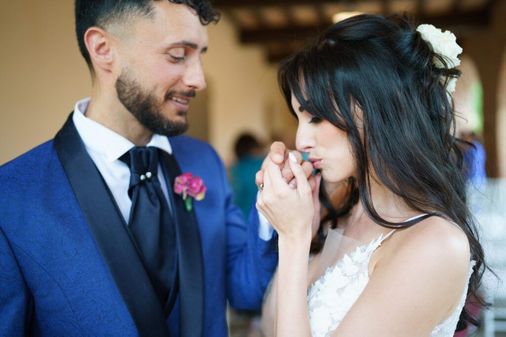 Couple shares tender moment during wedding ceremony while guests look on.