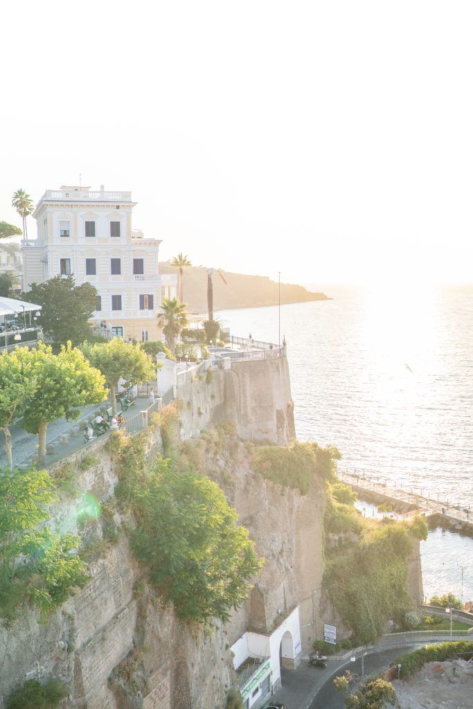 Scenic coastal view of cliffside buildings and Mediterranean architecture at sunset.