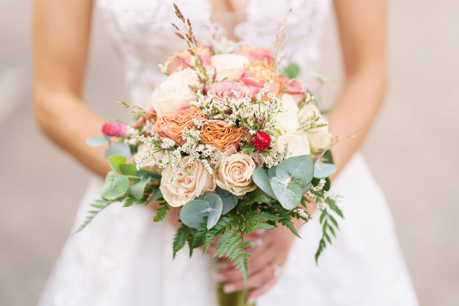 A delicate bridal bouquet featuring peach roses, white flowers and eucalyptus greenery.