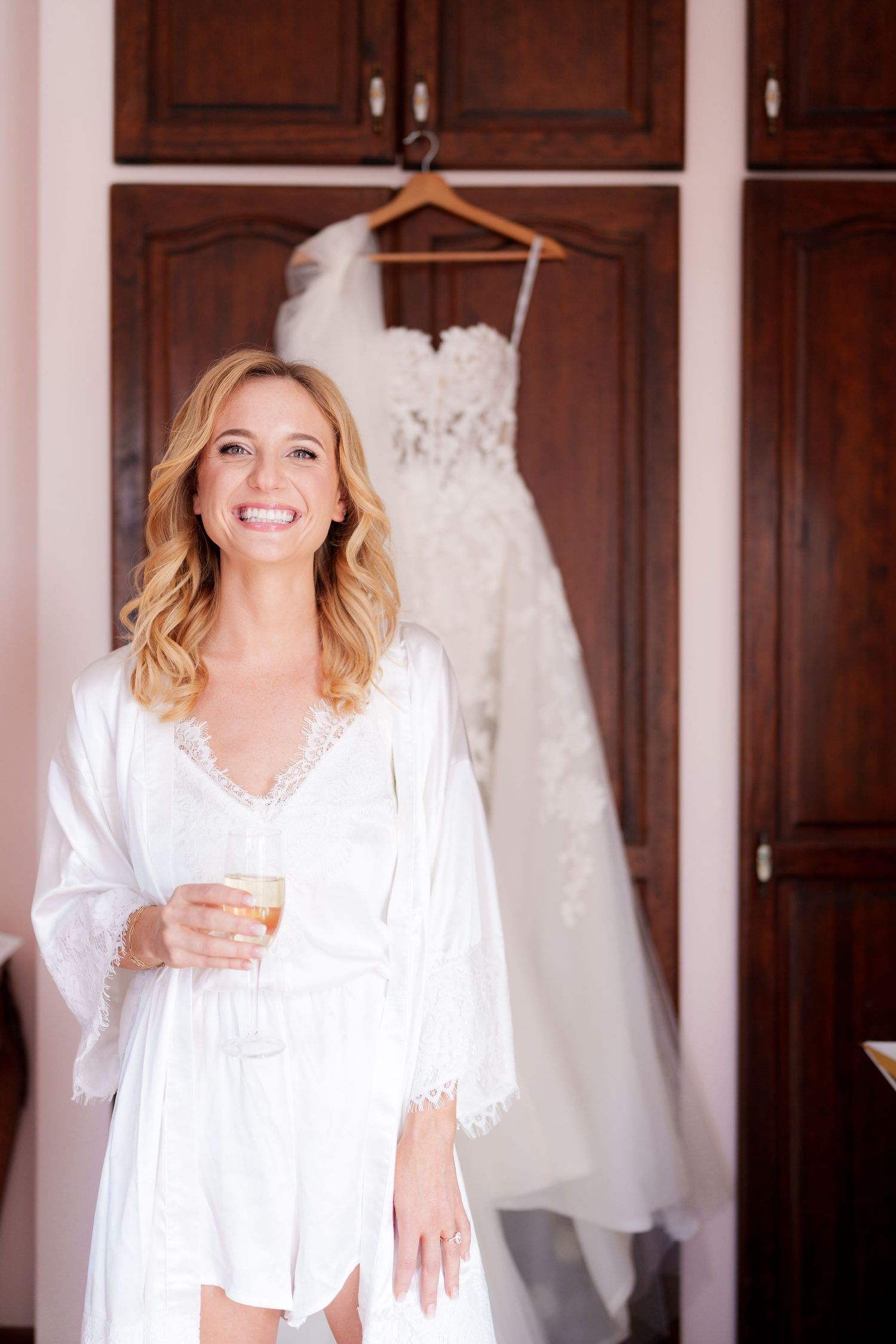 A group wearing white robes pose together in front of wedding dresses hanging on display.