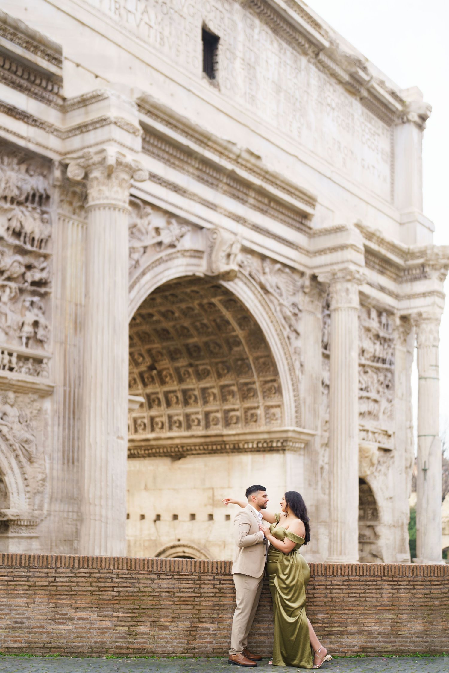 Couple embracing in front of the Arch of Constantine in Rome, Italy.