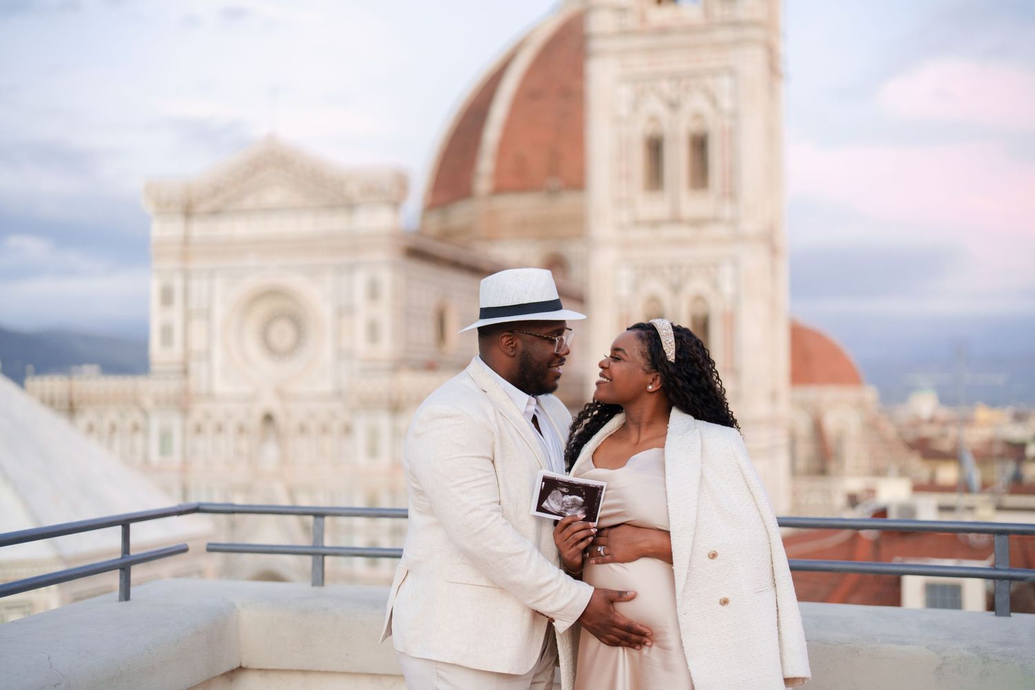 Couple sharing a romantic moment on a rooftop with Florence Cathedral dome backdrop at sunset.