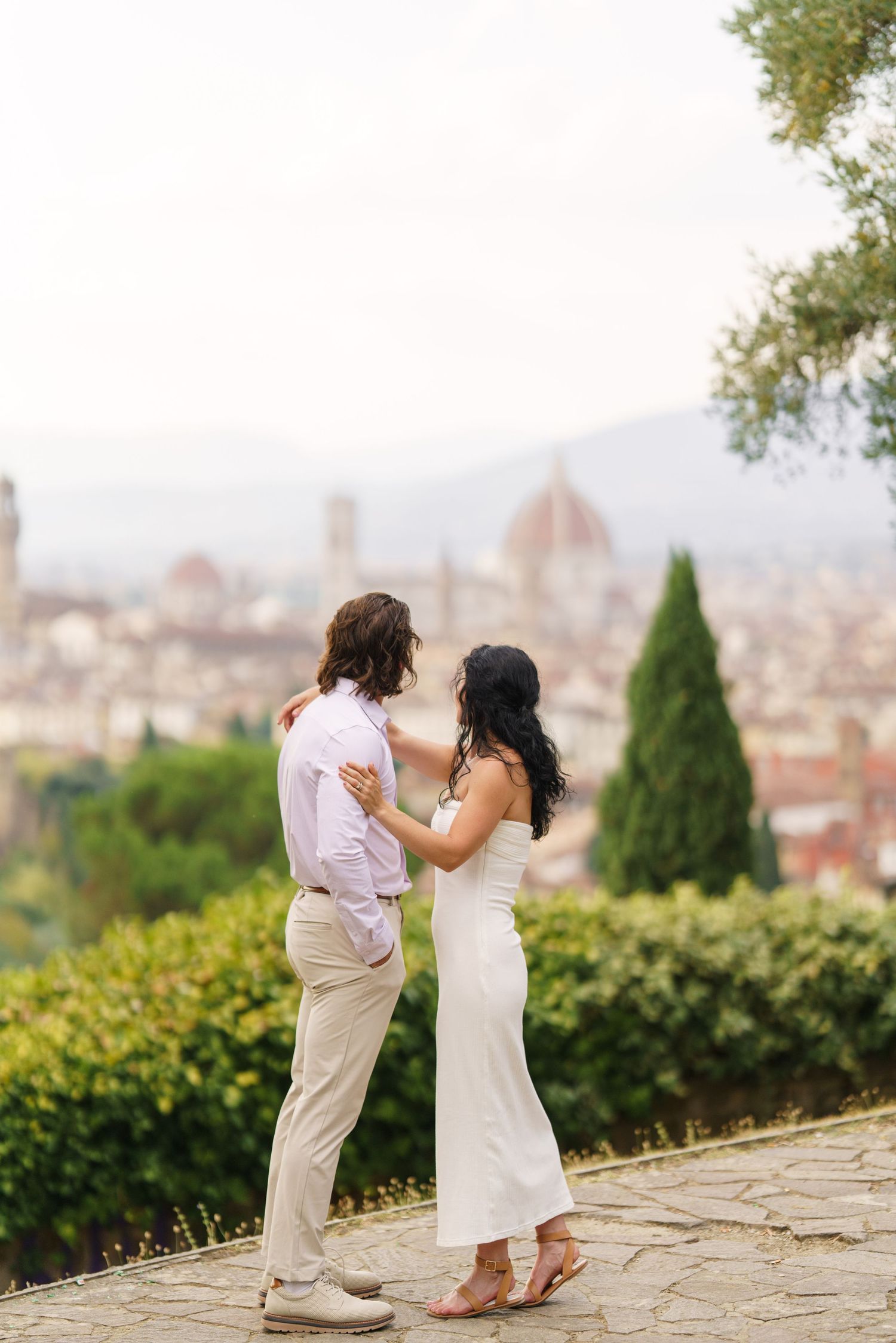 A romantic couple shares a tender moment overlooking the historic skyline of Florence, Italy from a scenic viewpoint.